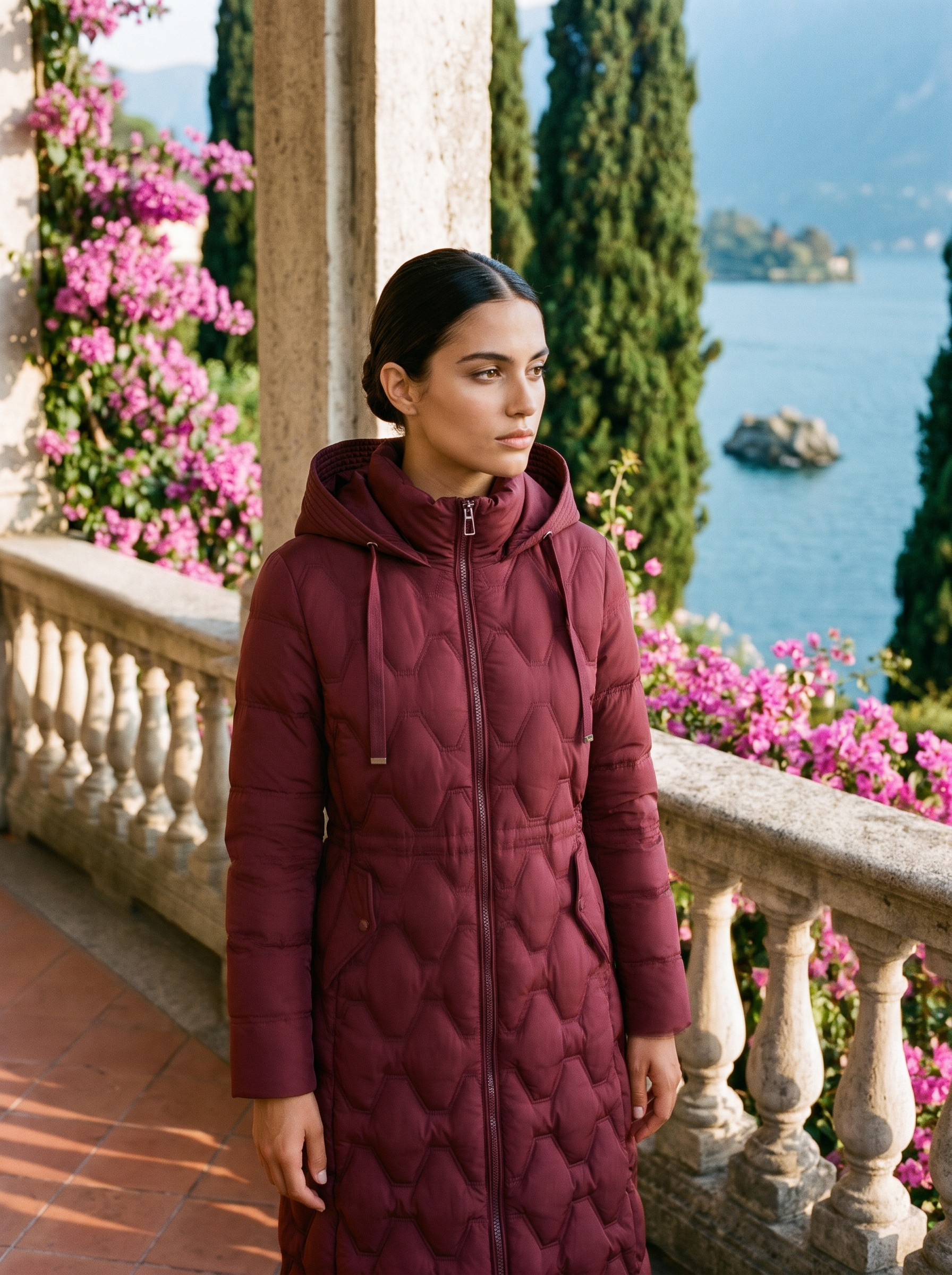 Woman wearing wine red onion-quilted longline hooded puffer coat on a Lake Como terrace