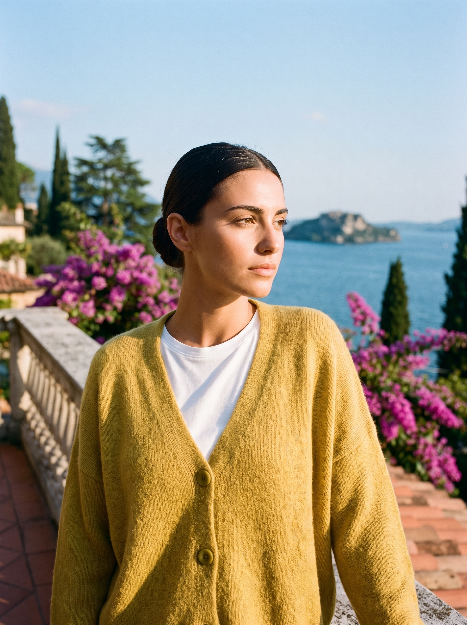 Woman wearing a yellow V-neck cardigan on a terrace overlooking Lake Como, old money style — Aveloire