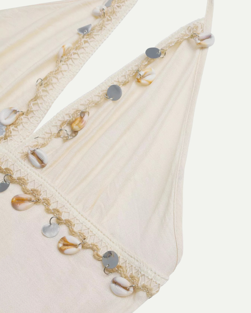 Close-up of a decorative white fabric with gold and silver embellishments on a white background