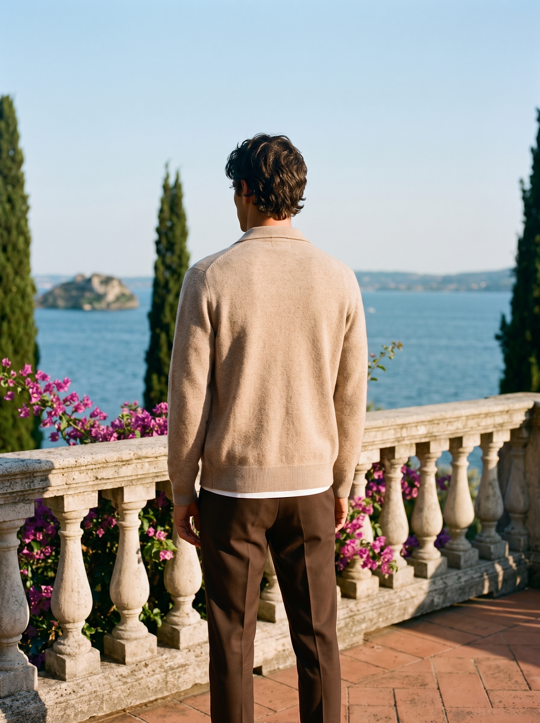 Back view of a beige mercerized wool zip-up collared cardigan worn on a Mediterranean terrace — Aveloire