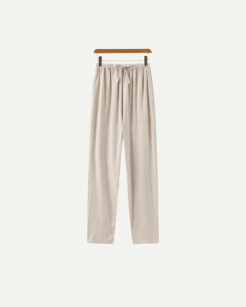 Beige linen pants on a hanger against a white background