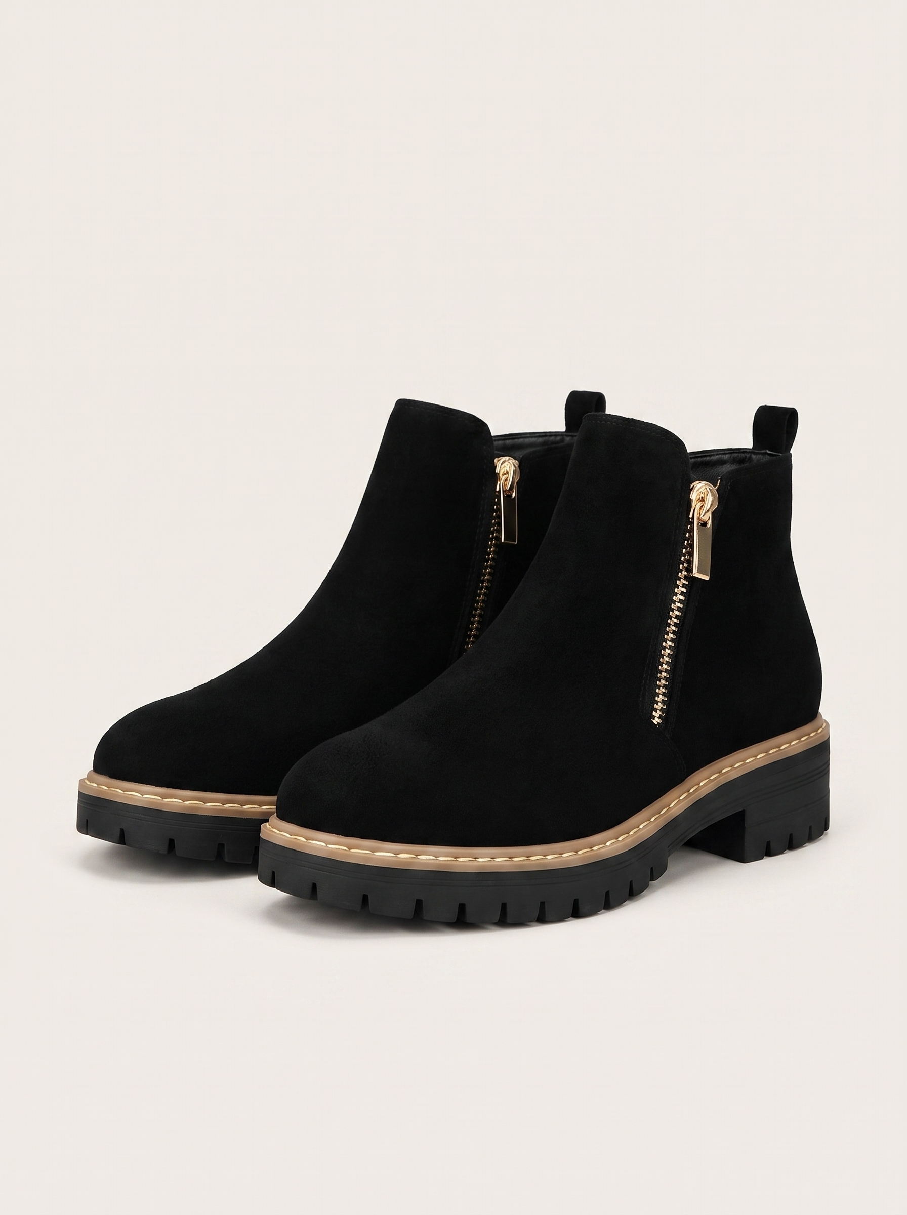 Pair of black suede-look lug sole ankle boots on off-white background