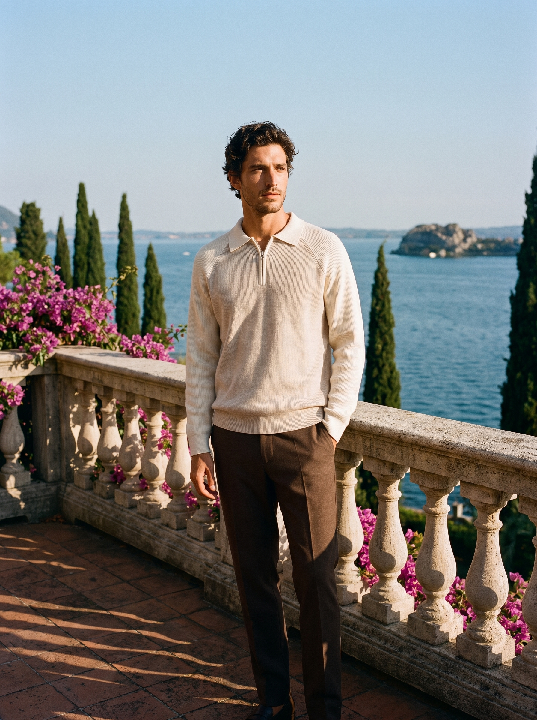 Full body view of a man in a cream half-zip knit polo sweater and brown trousers on a Lake Como terrace — Aveloire