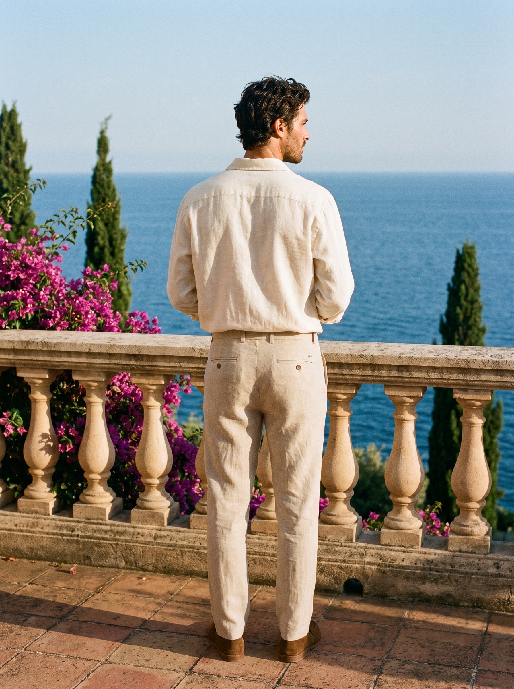 Back view of a man in beige tailored linen trousers overlooking Lake Como — Aveloire
