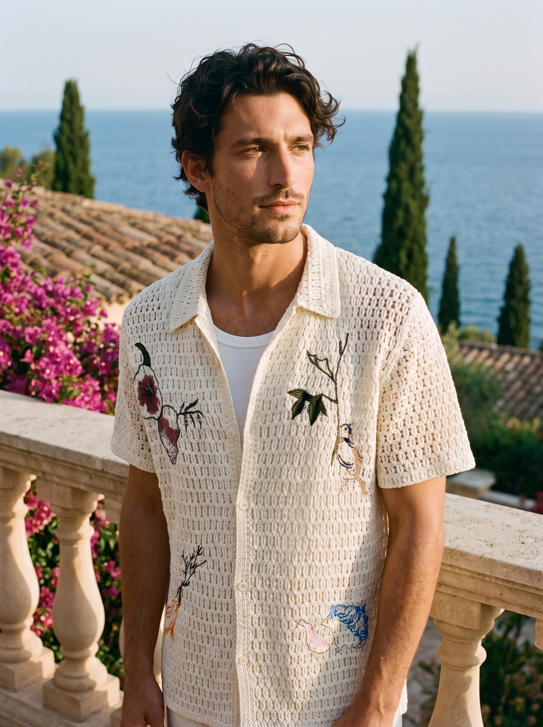 Man wearing an ivory embroidered crochet shirt on a balcony overlooking Lake Como, old money style — Aveloire