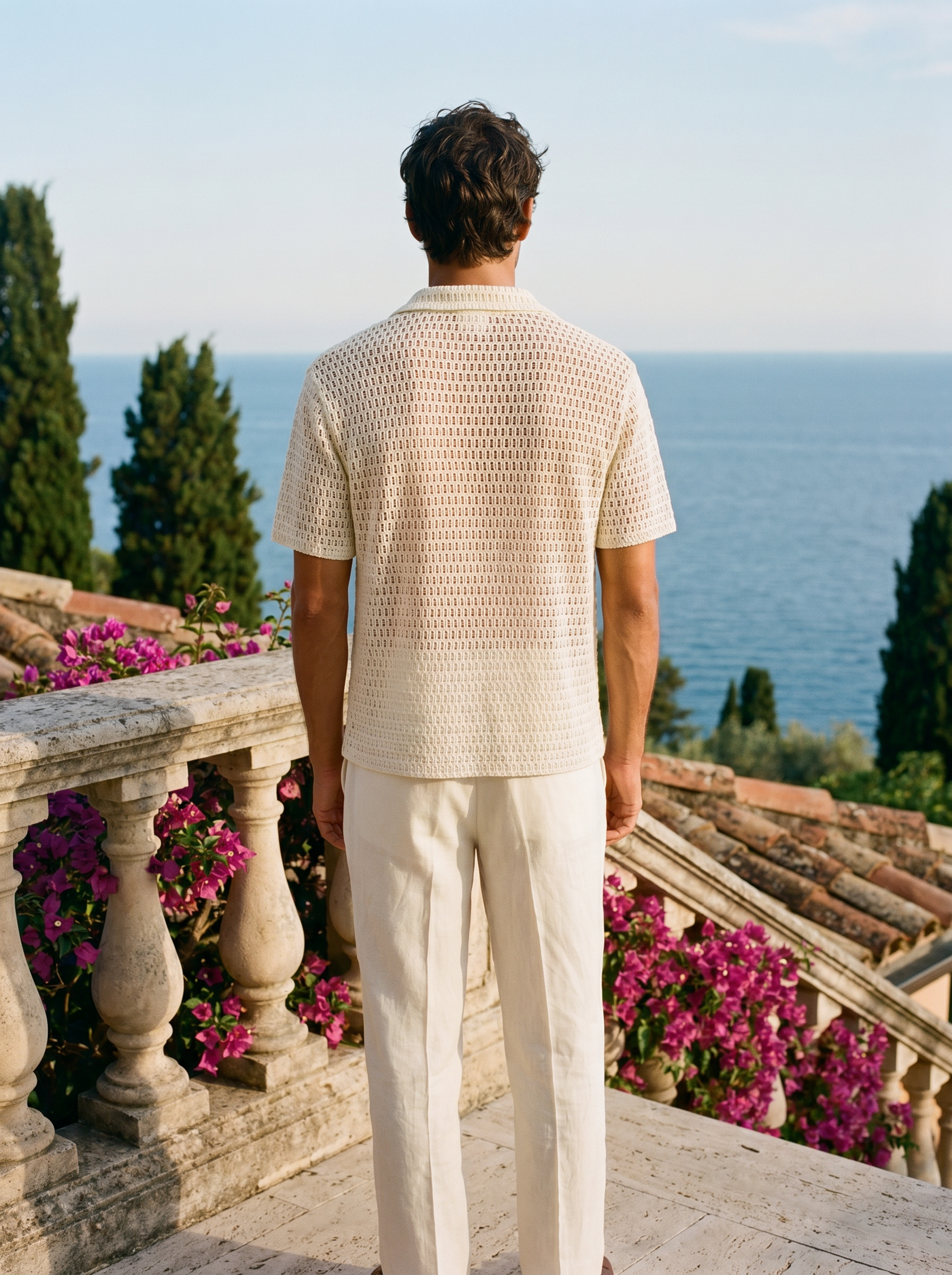 Back view of a man in an ivory embroidered crochet shirt overlooking Lake Como — Aveloire