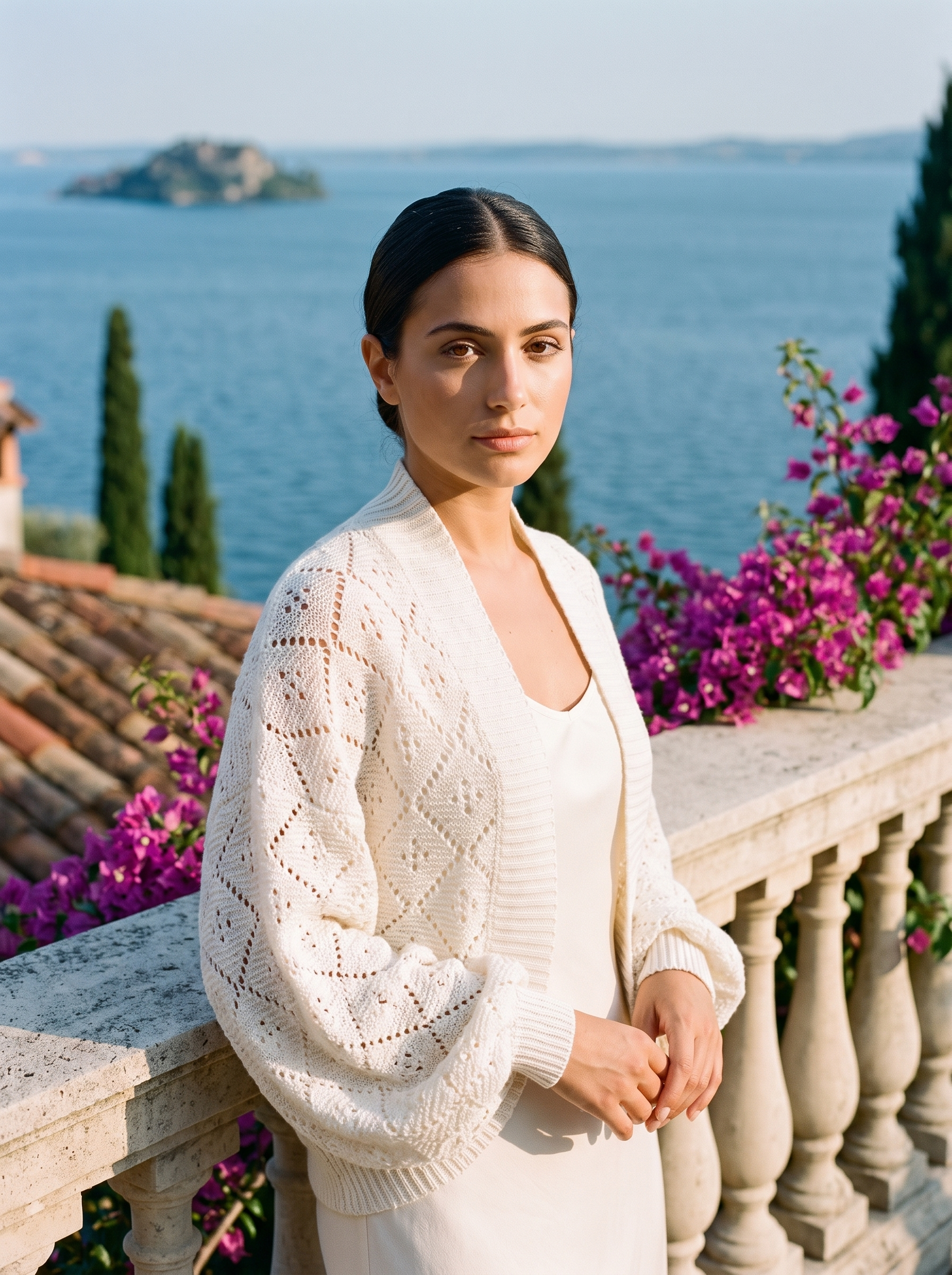 Woman wearing an off-white cropped open-front knit shrug cardigan on a Lake Como terrace — Aveloire