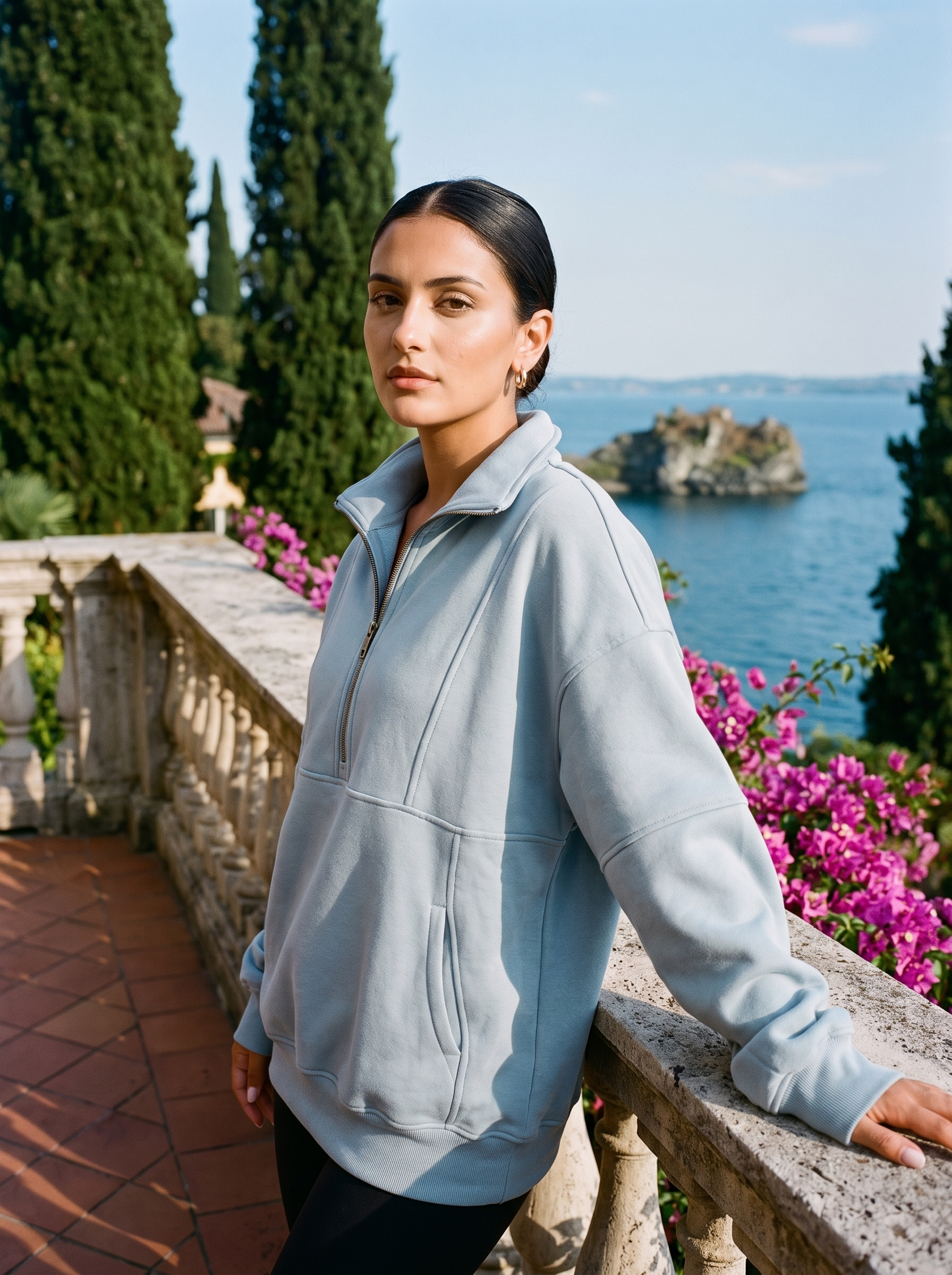 Woman wearing a light blue oversized half-zip pocket sweatshirt on a Lake Como terrace — Aveloire