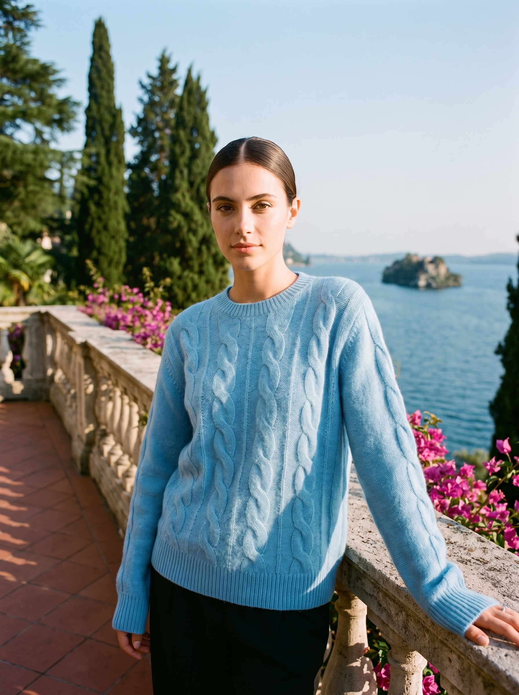 Woman wearing a sky blue cable-knit crew neck sweater on a Lake Como terrace — Aveloire