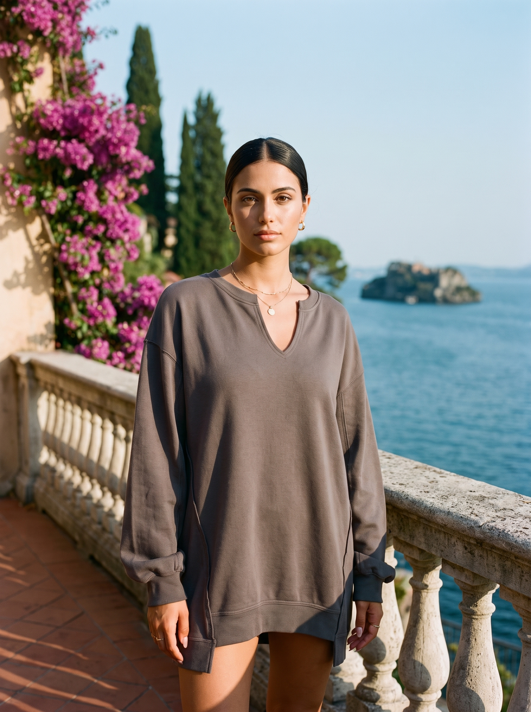 Woman wearing a dark grey V-neck sweatshirt tunic on a Lake Como terrace, old money style — Aveloire