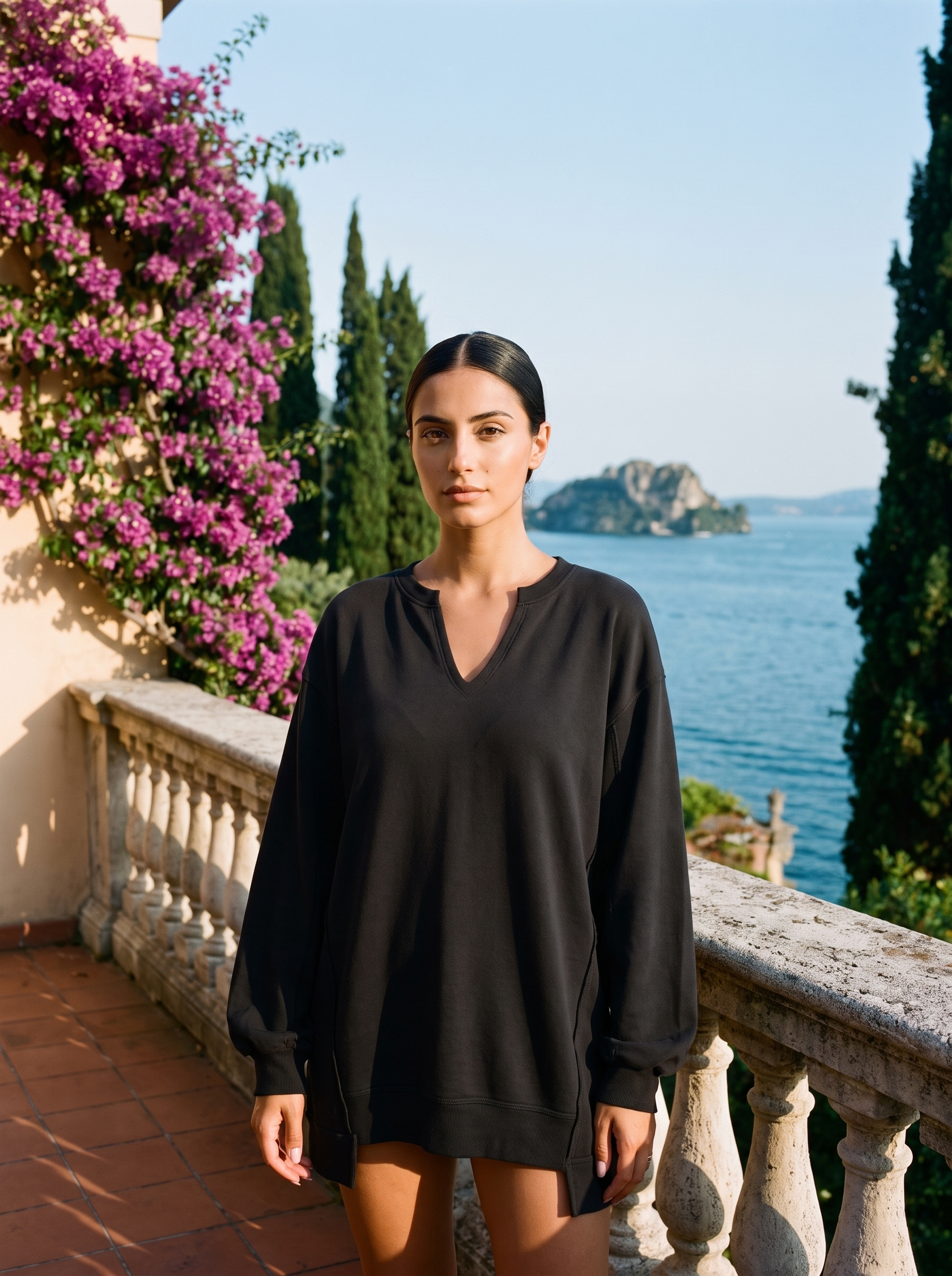Woman wearing a black V-neck sweatshirt tunic on a Lake Como terrace, old money style — Aveloire