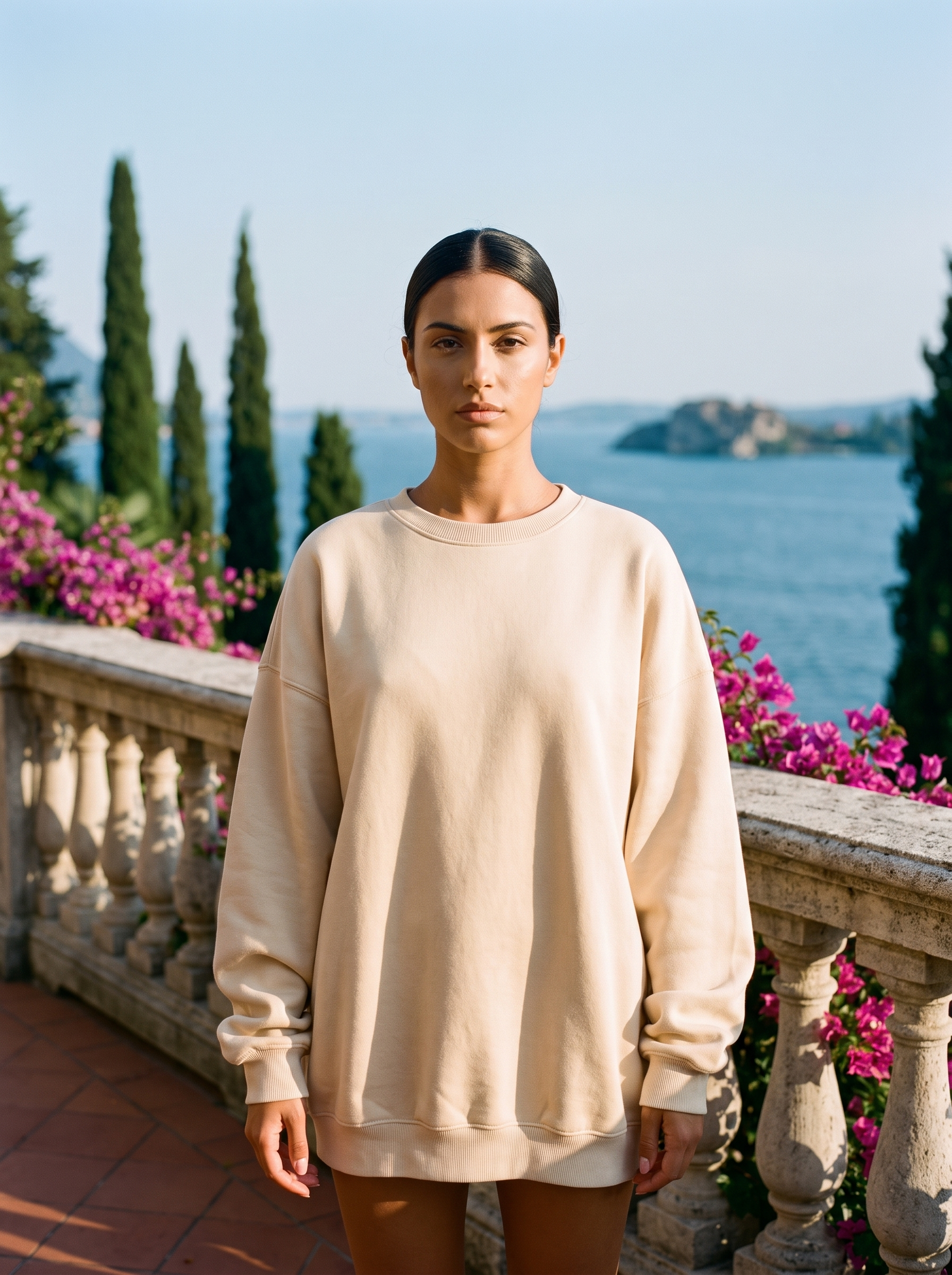 Woman wearing a cream beige oversized crew neck sweatshirt on a Lake Como terrace, old money style — Aveloire