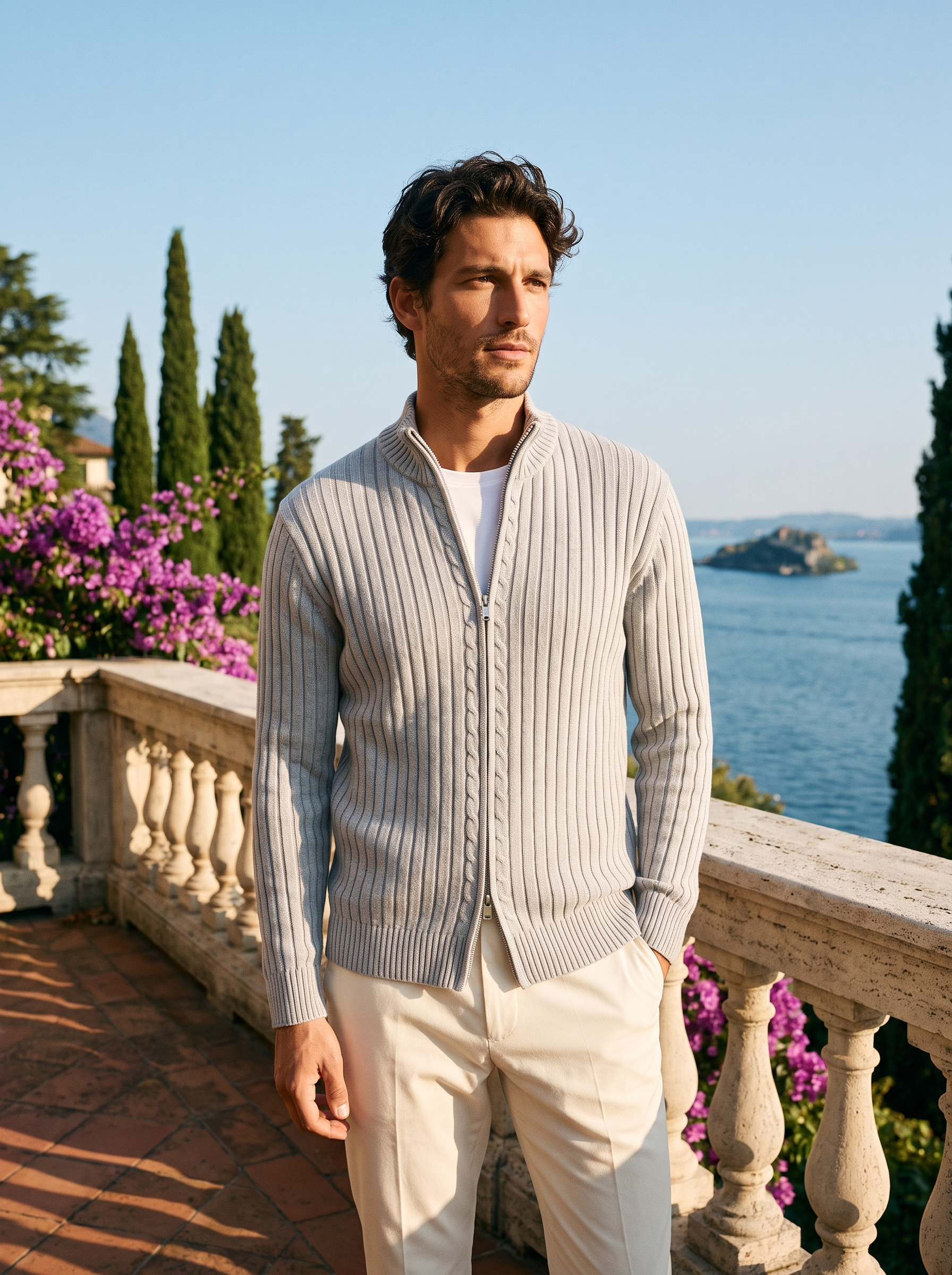 Full body view of a man in a light gray ribbed cotton zip cardigan and cream trousers on a Lake Como terrace — Aveloire