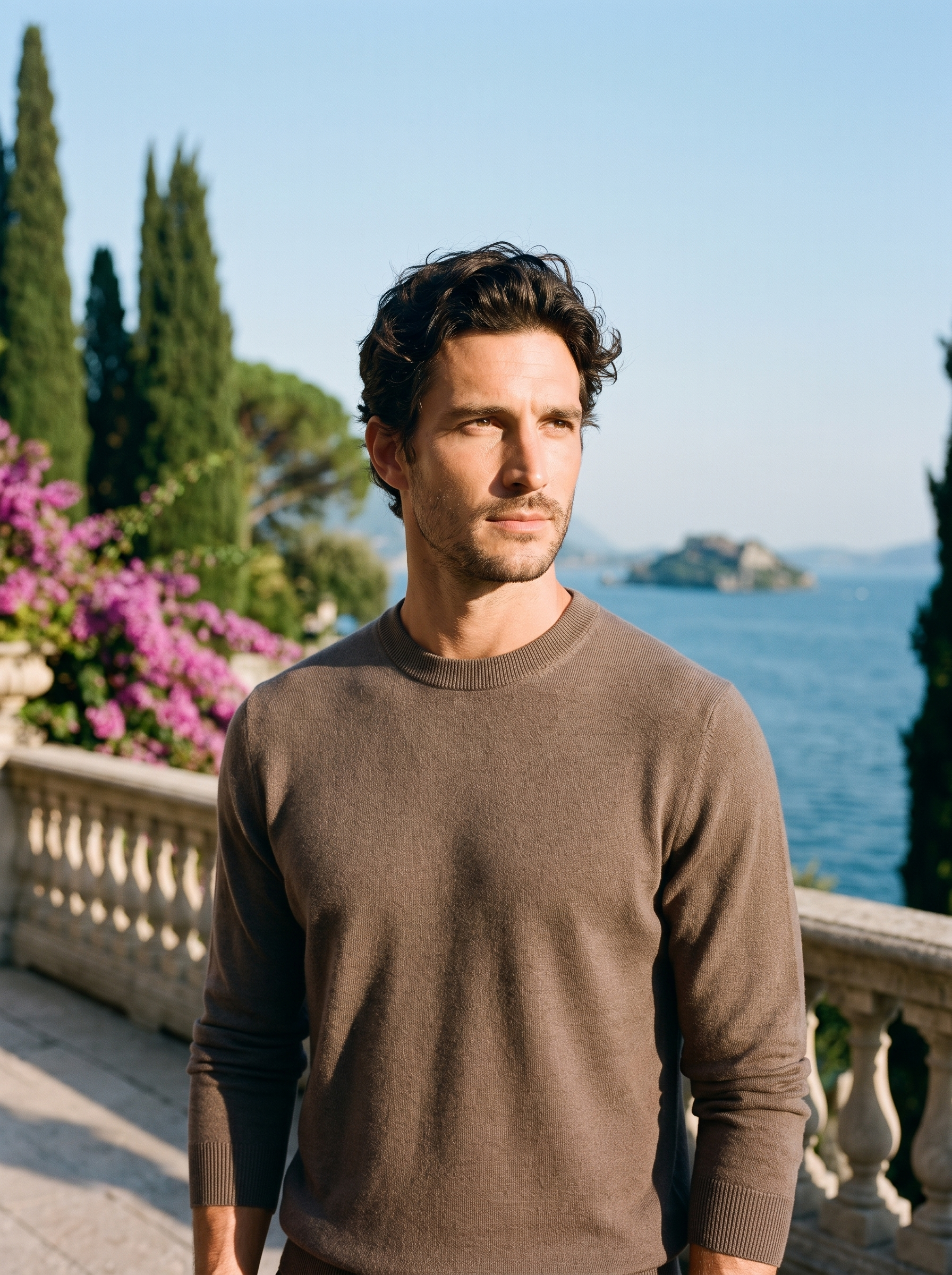 Man wearing a brown 100% wool crewneck sweater on a terrace overlooking Lake Como, old money style — Aveloire