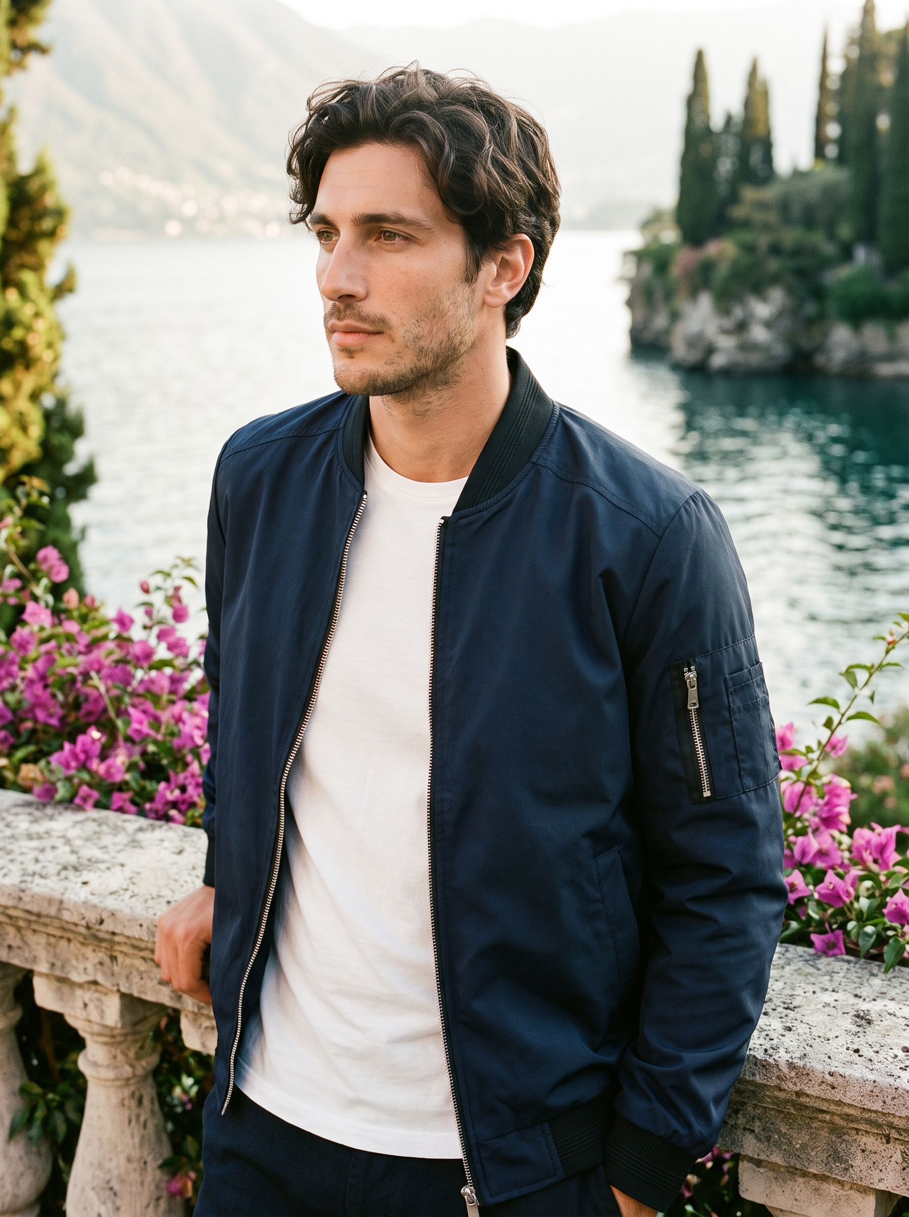 Man wearing a dark blue bomber jacket on a terrace overlooking Lake Como, old money style — Aveloire