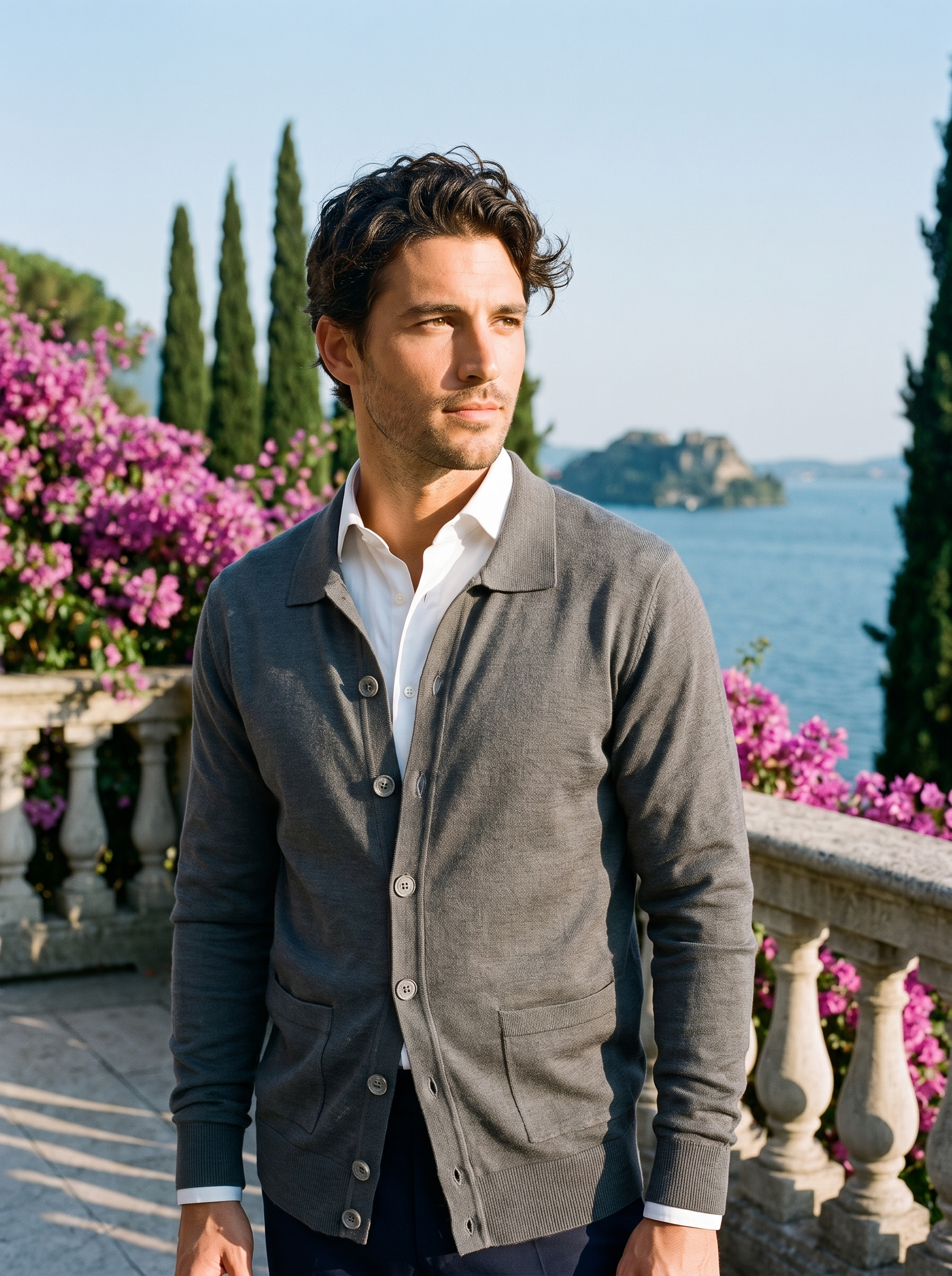 Man wearing a gray button-up collared cardigan on a terrace overlooking Lake Como, old money style — Aveloire