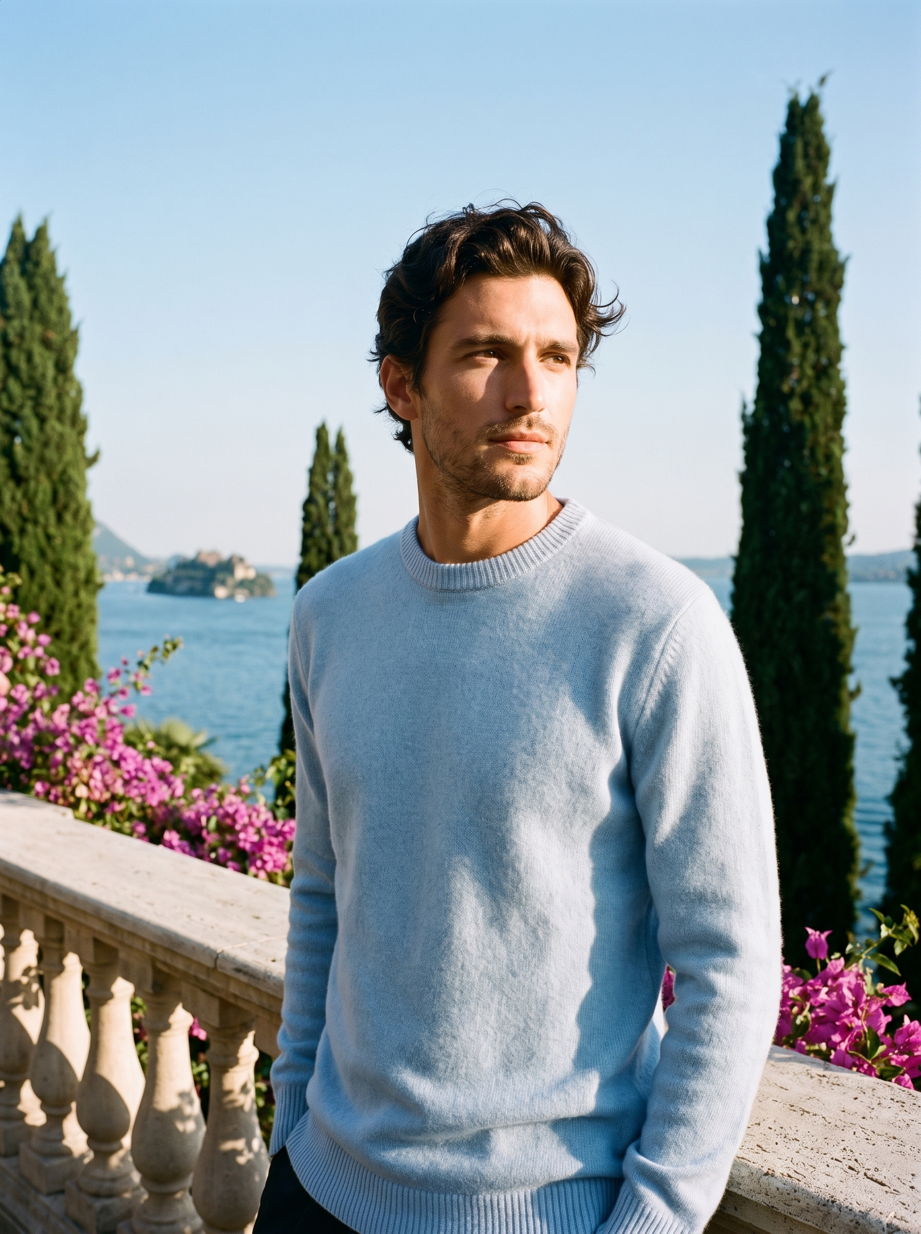 Man wearing a light blue classic crewneck sweater on a terrace overlooking Lake Como, old money style — Aveloire