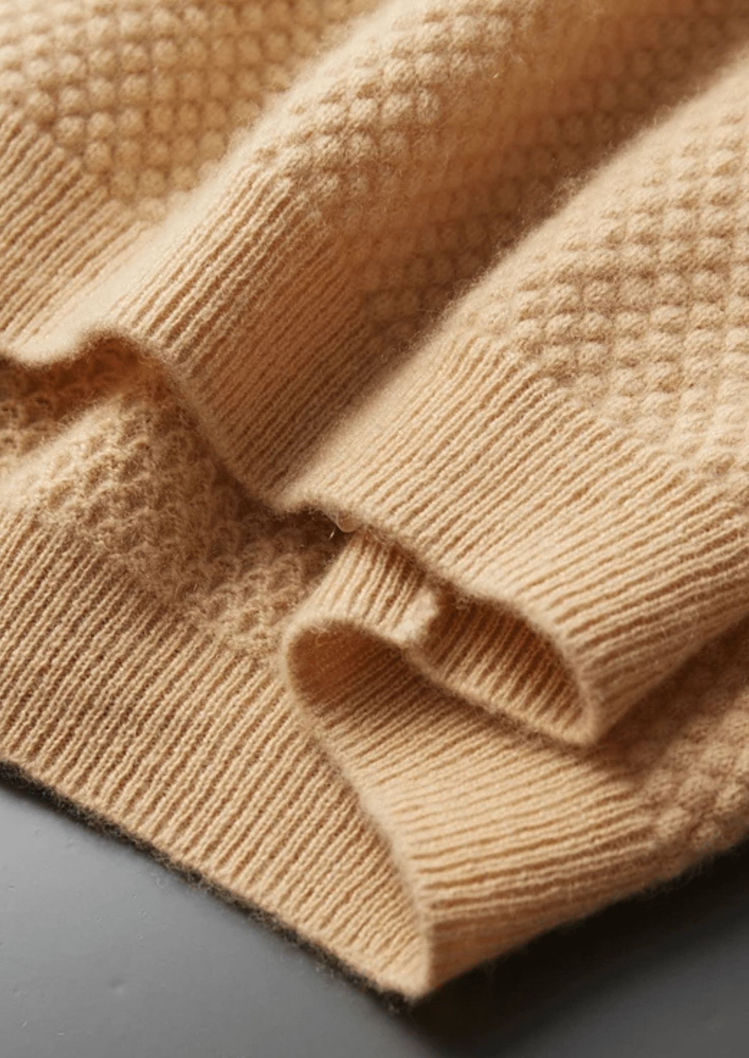 Close-up of a beige knitted fabric with a textured pattern.