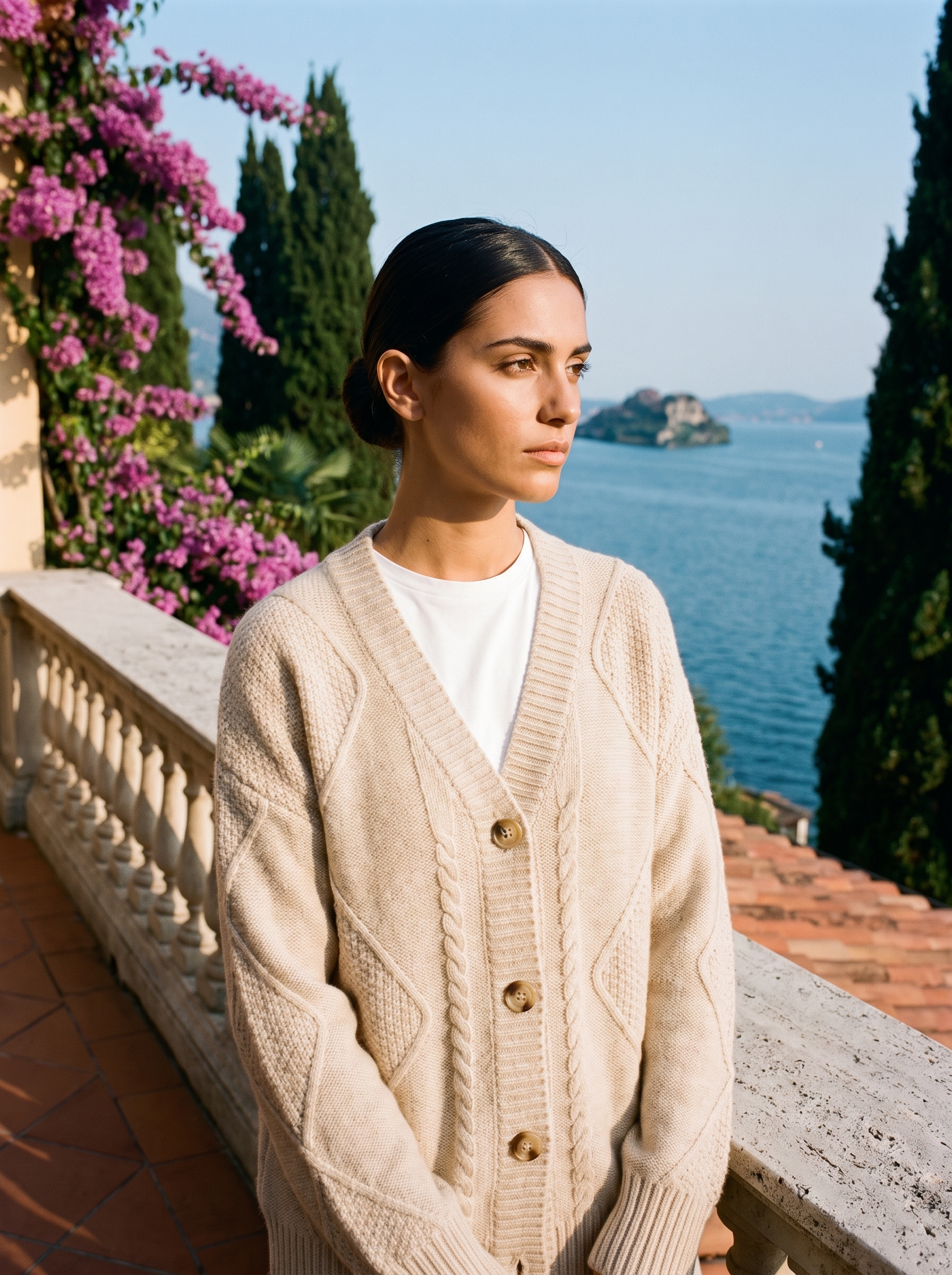 Woman wearing a beige cable-knit cardigan on a terrace overlooking Lake Como, old money style — Aveloire