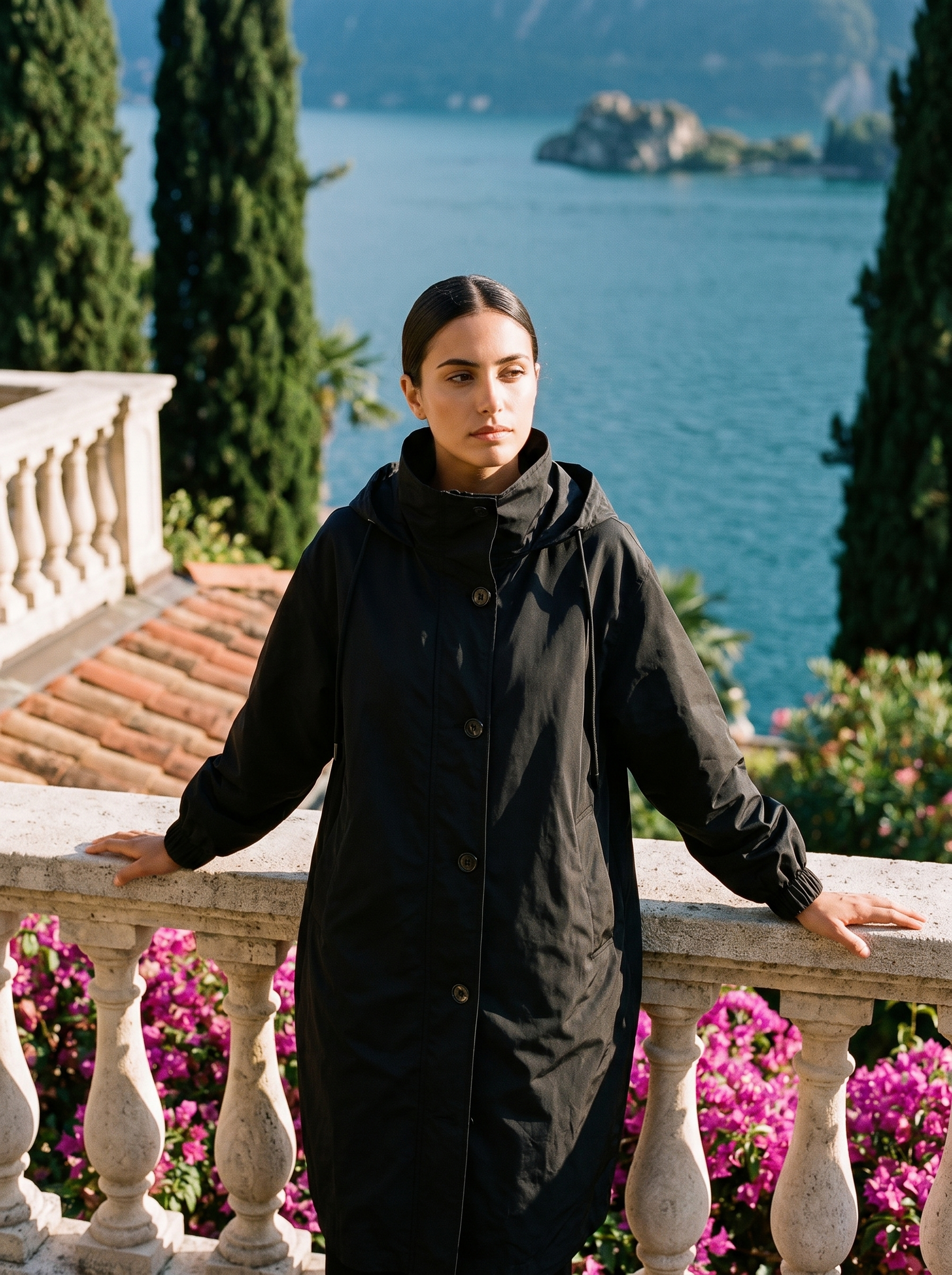 Woman wearing black water-repellent hooded raincoat on a Lake Como terrace