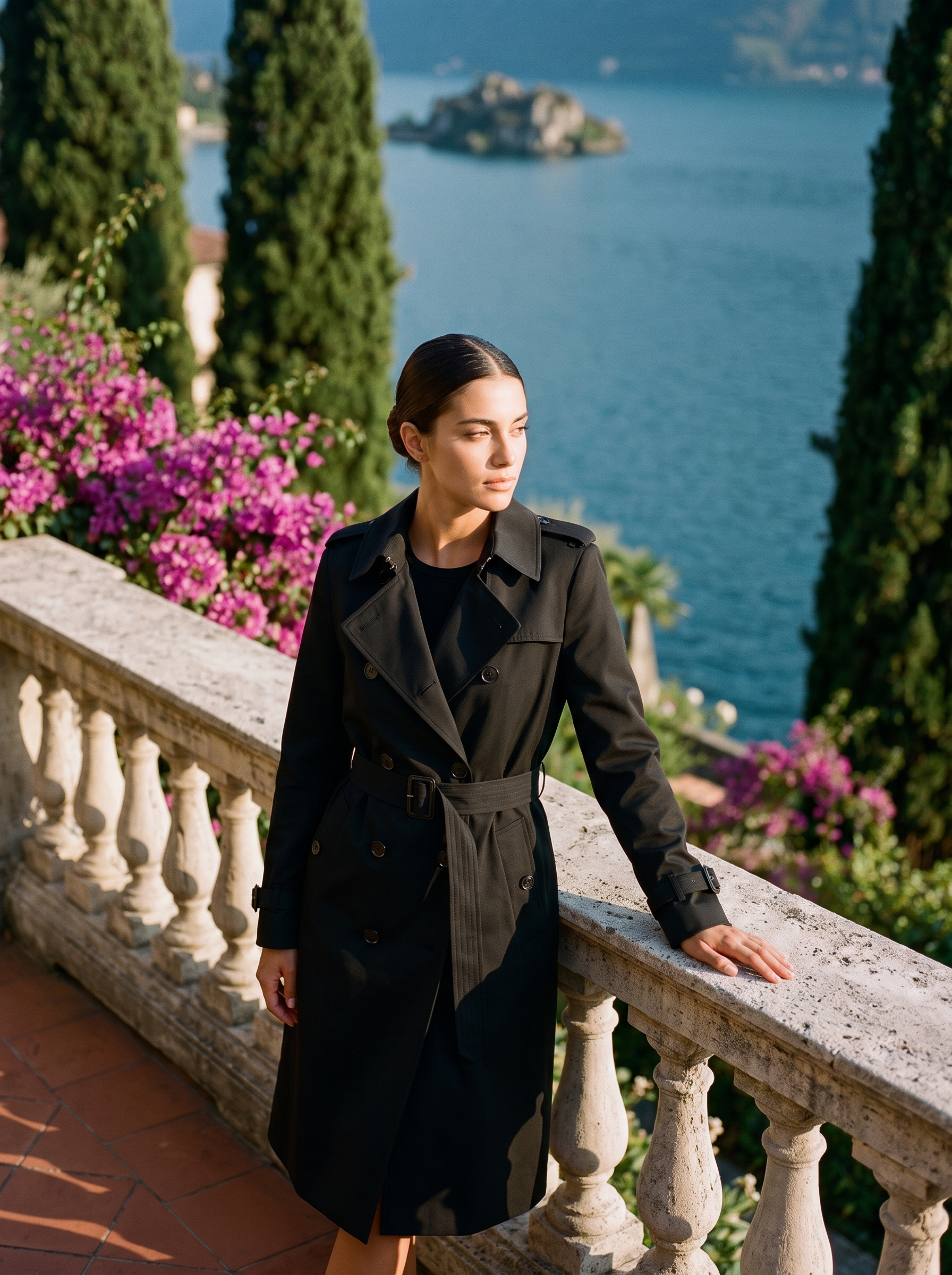 Woman wearing a black double-breasted belted trench coat on a Lake Como terrace — Aveloire