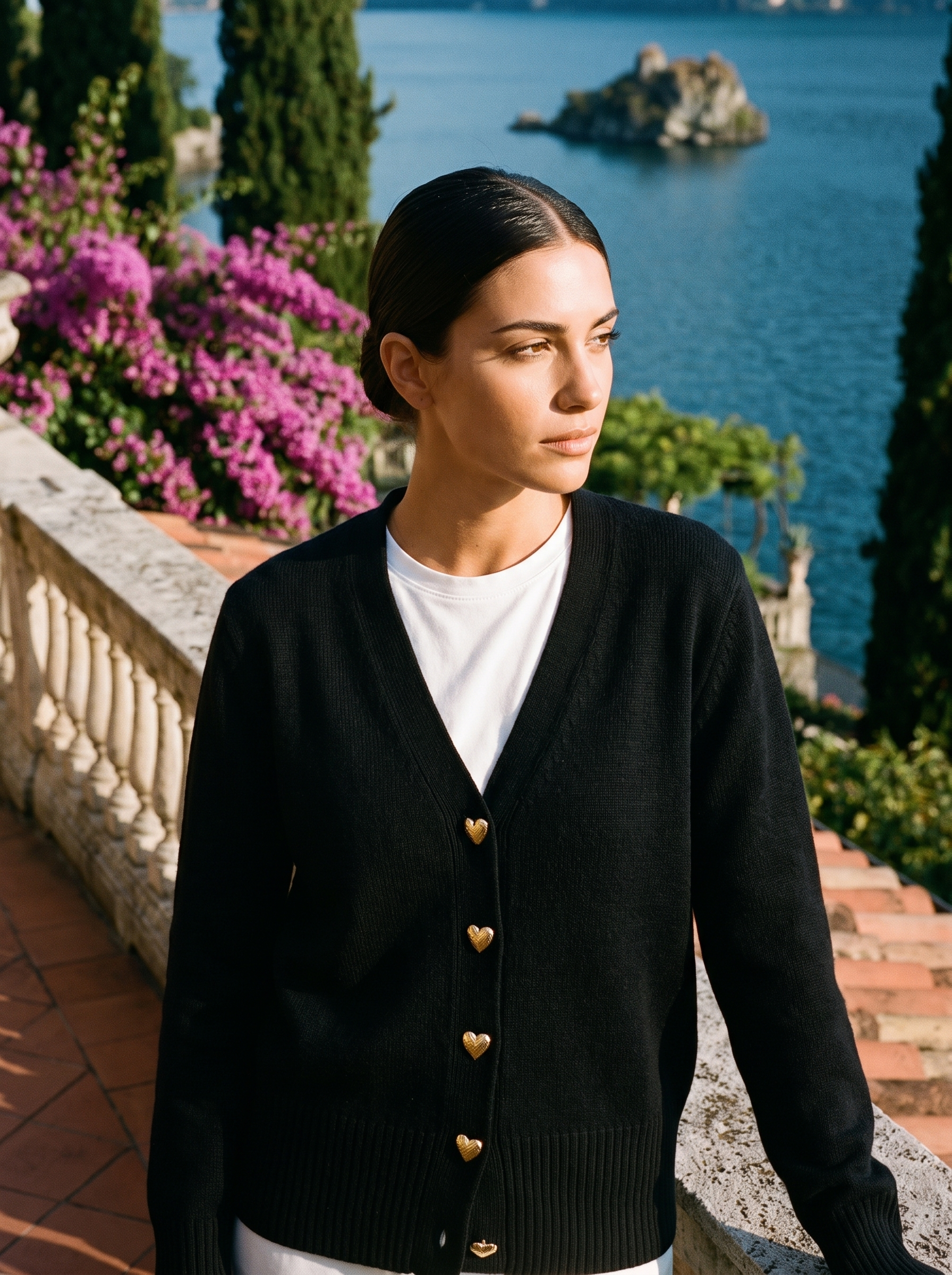 Woman wearing a black V-neck button cardigan on a terrace overlooking Lake Como, old money style — Aveloire