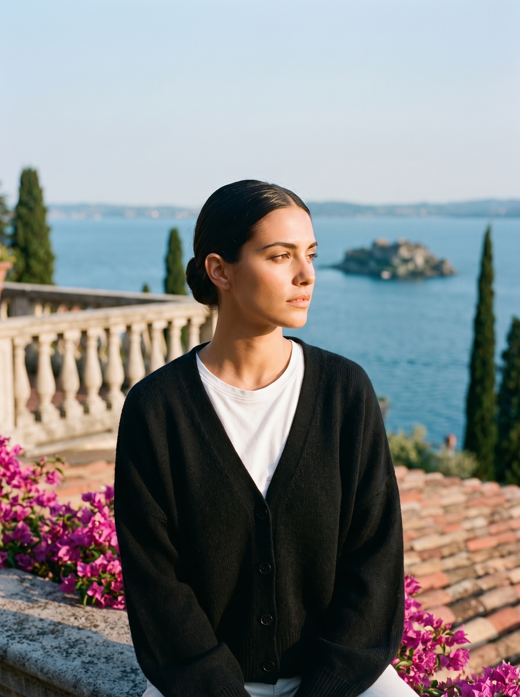 Woman wearing a black V-neck cardigan on a terrace overlooking Lake Como, old money style — Aveloire