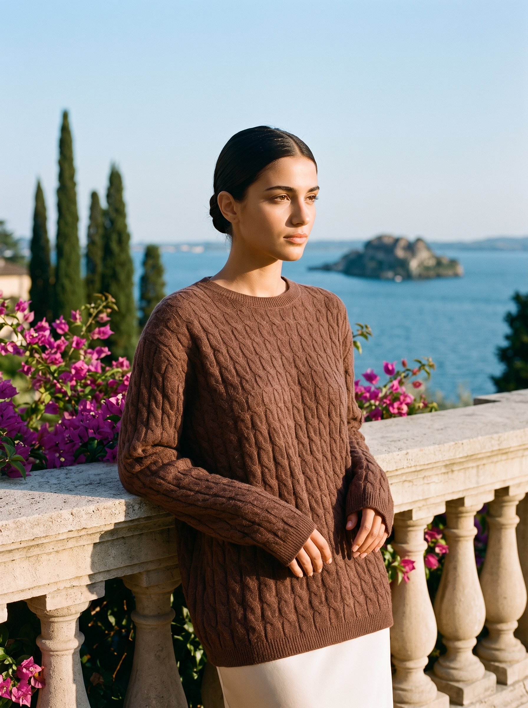 Woman wearing a brown cable-knit jumper on a terrace overlooking Lake Como — Aveloire