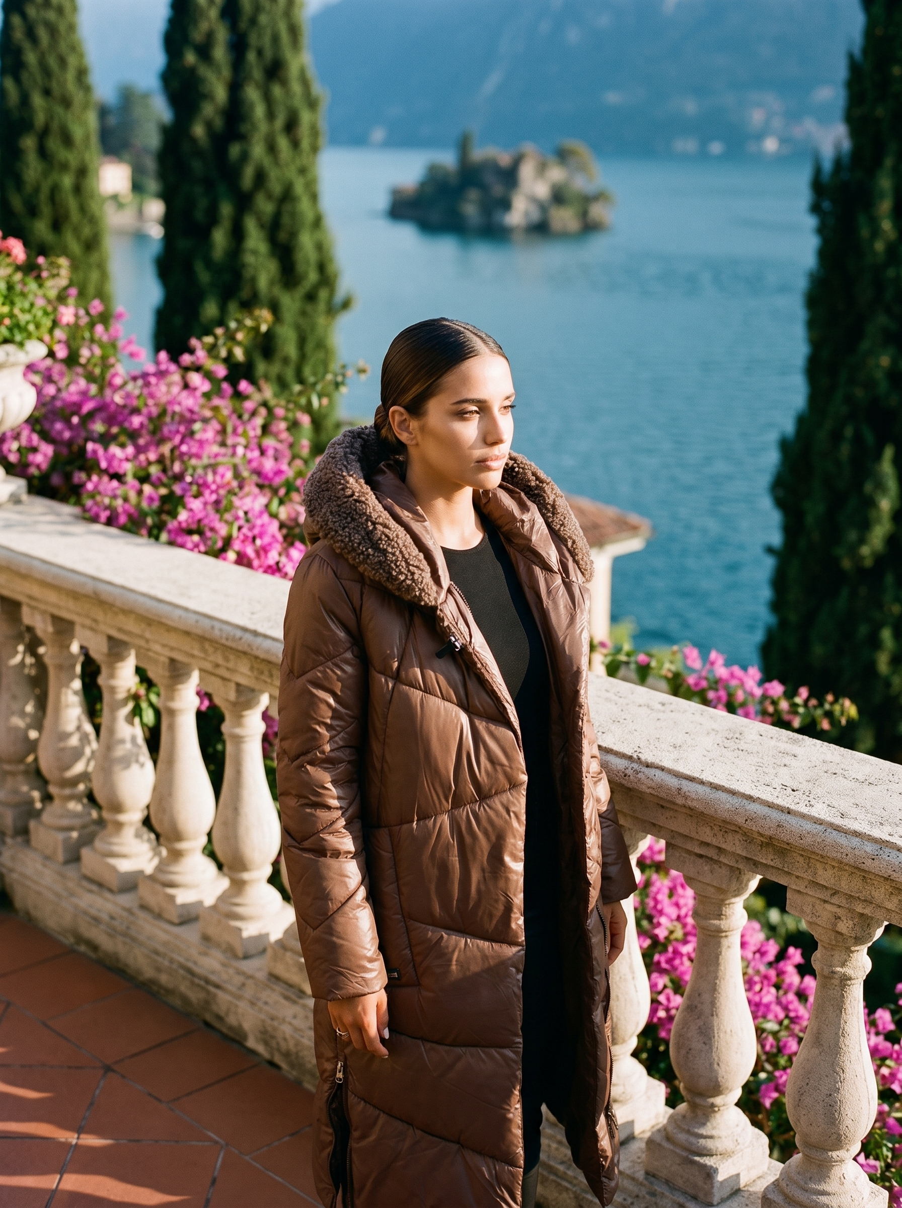 Woman wearing a chocolate-brown quilted hooded puffer coat on a Lake Como terrace — Aveloire