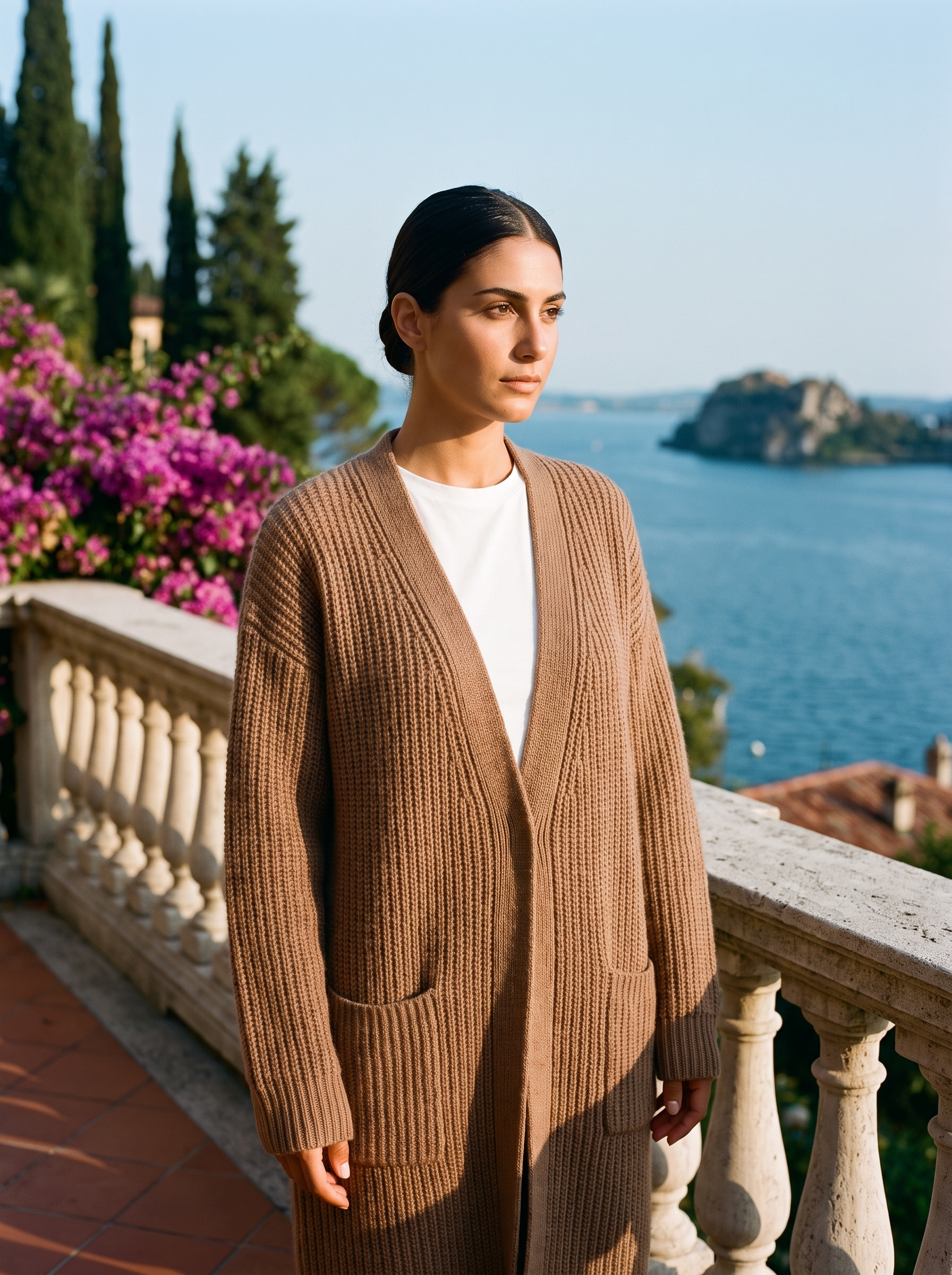 Woman wearing a brown open-front knit cardigan on a terrace overlooking Lake Como, old money style — Aveloire