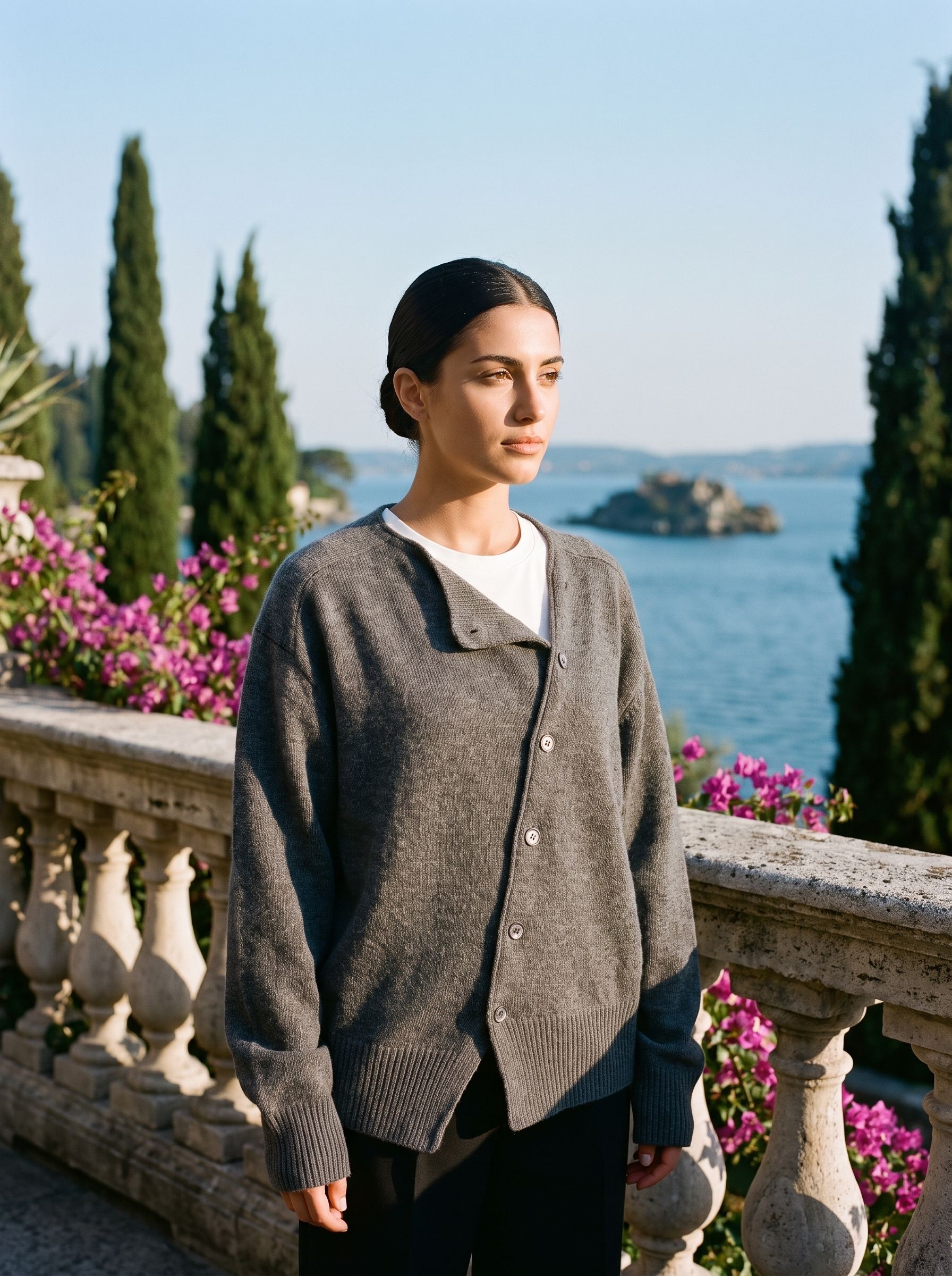 Woman wearing a gray knit cardigan on a terrace overlooking Lake Como, old money style — Aveloire