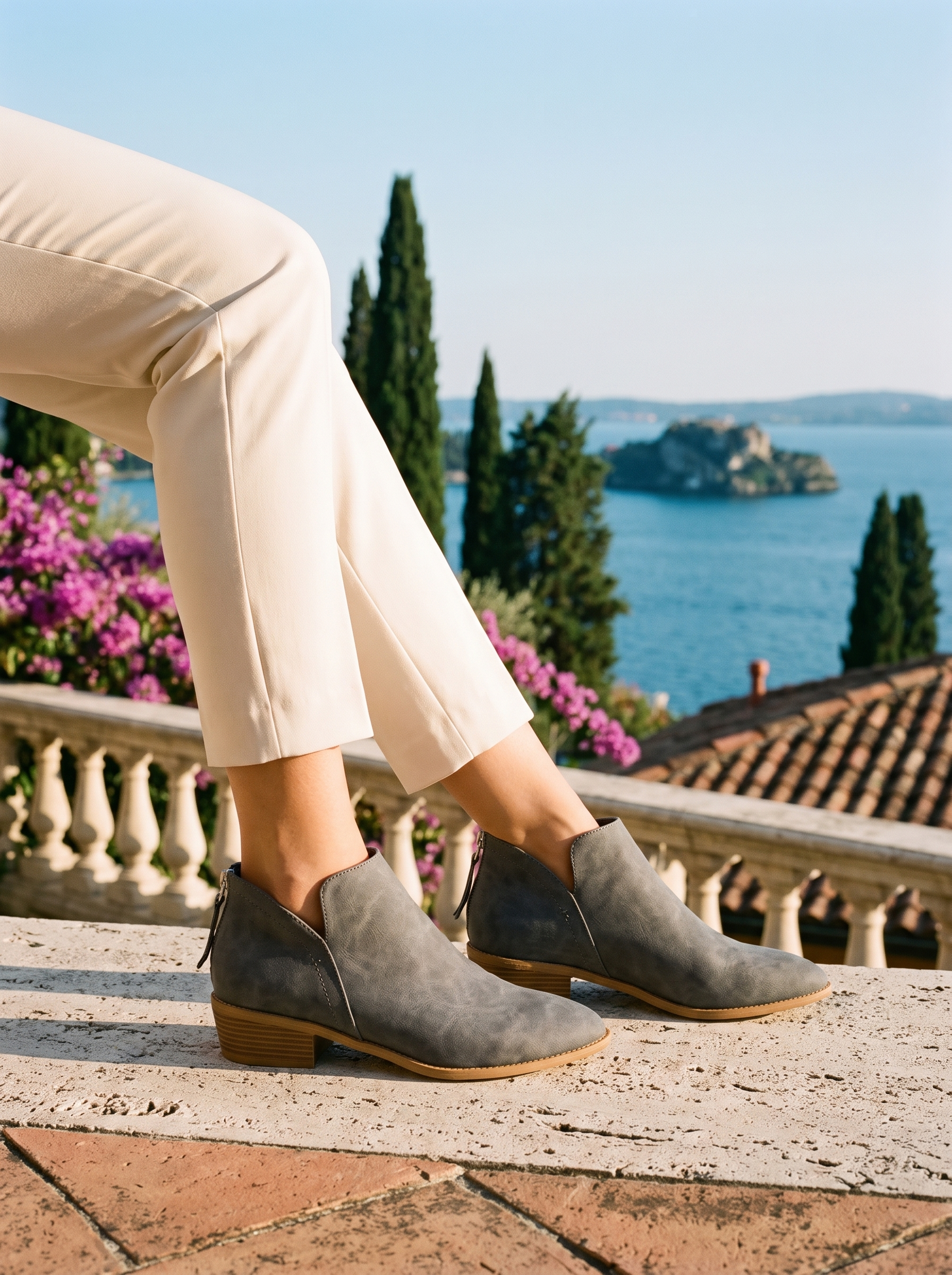 Woman wearing gray suede V-cut ankle boots on a terrace overlooking Lake Como — Aveloire