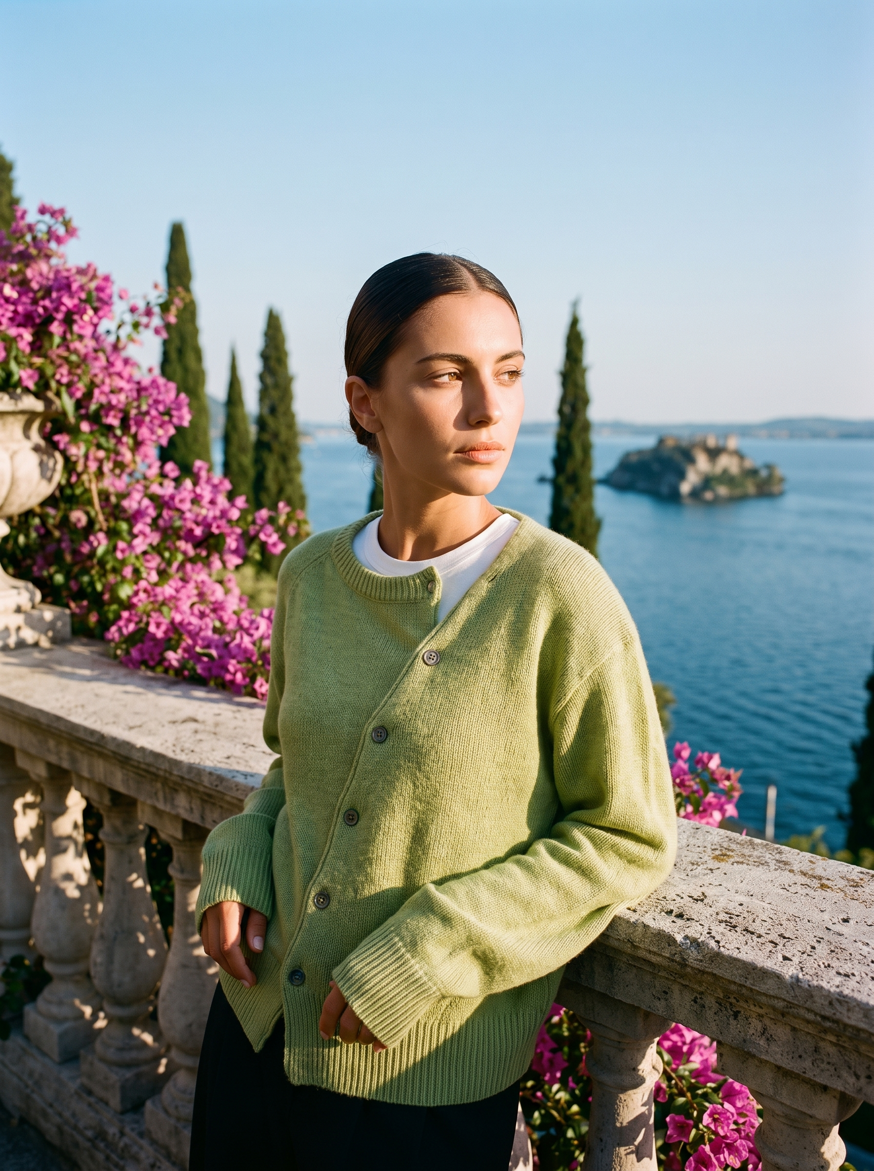 Woman wearing a green knit cardigan on a terrace overlooking Lake Como, old money style — Aveloire