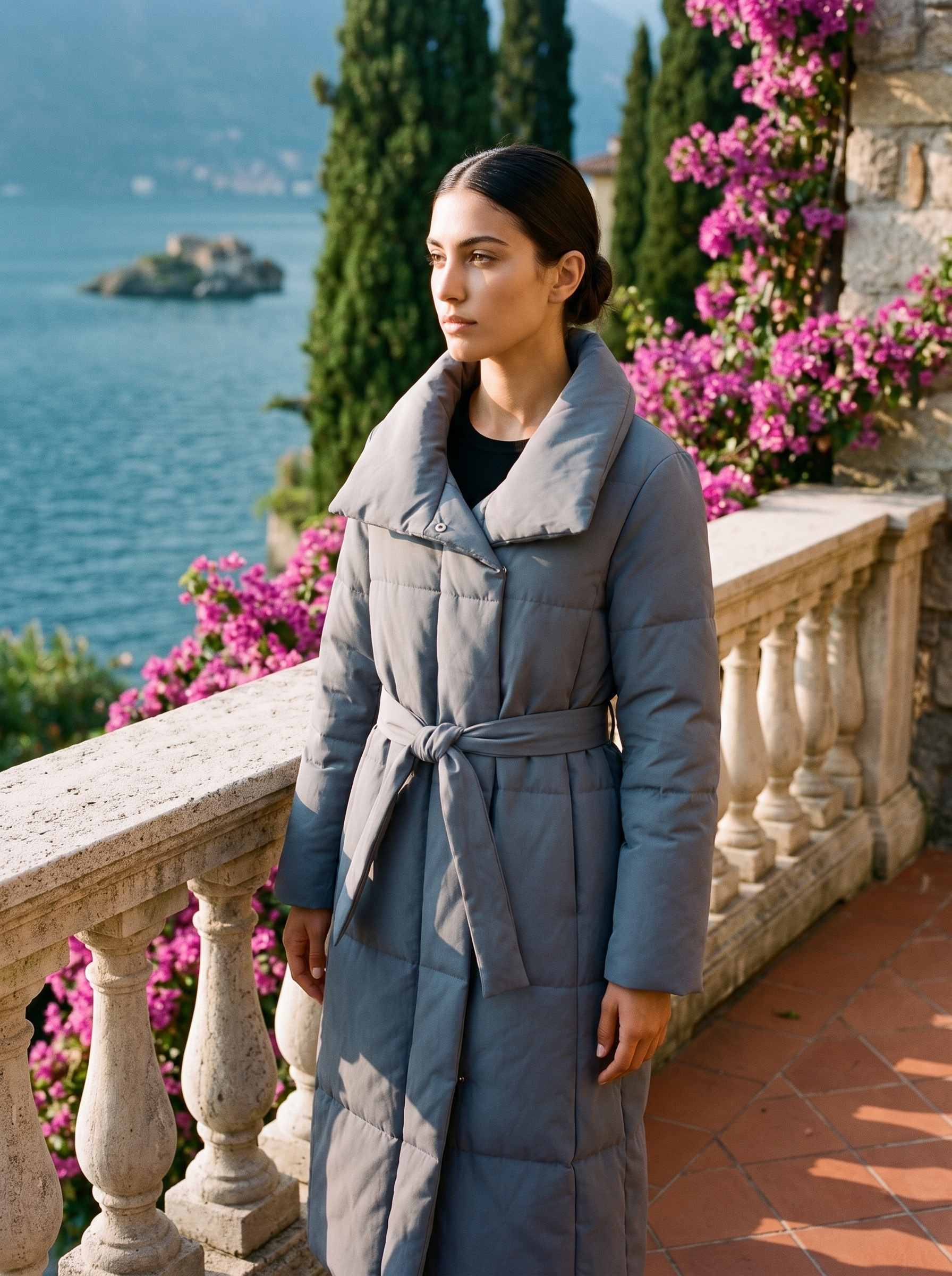 Woman wearing a slate-grey belted quilted coat on a Lake Como terrace — Aveloire