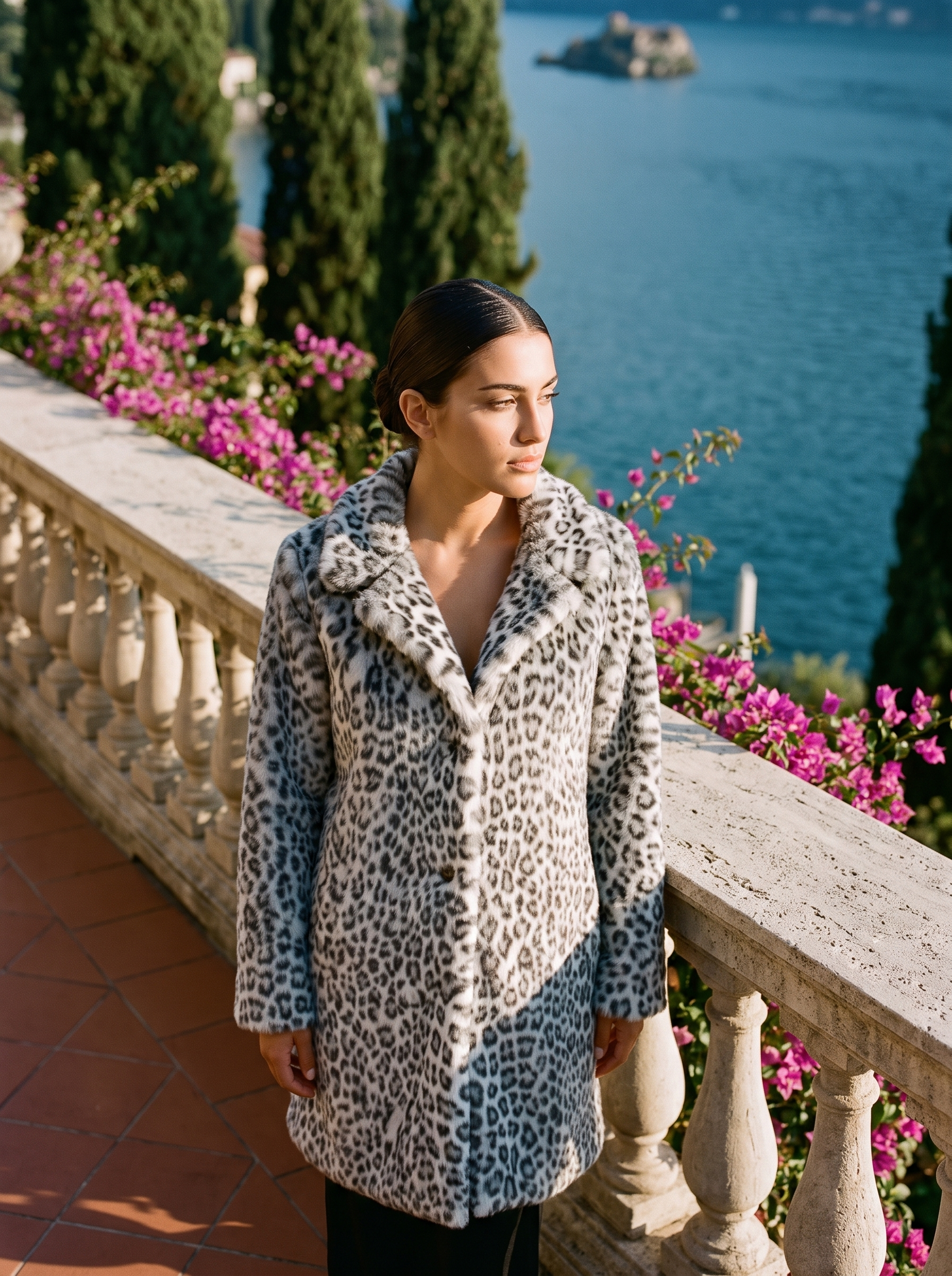 Woman wearing grey snow-leopard print faux fur coat on a Lake Como terrace