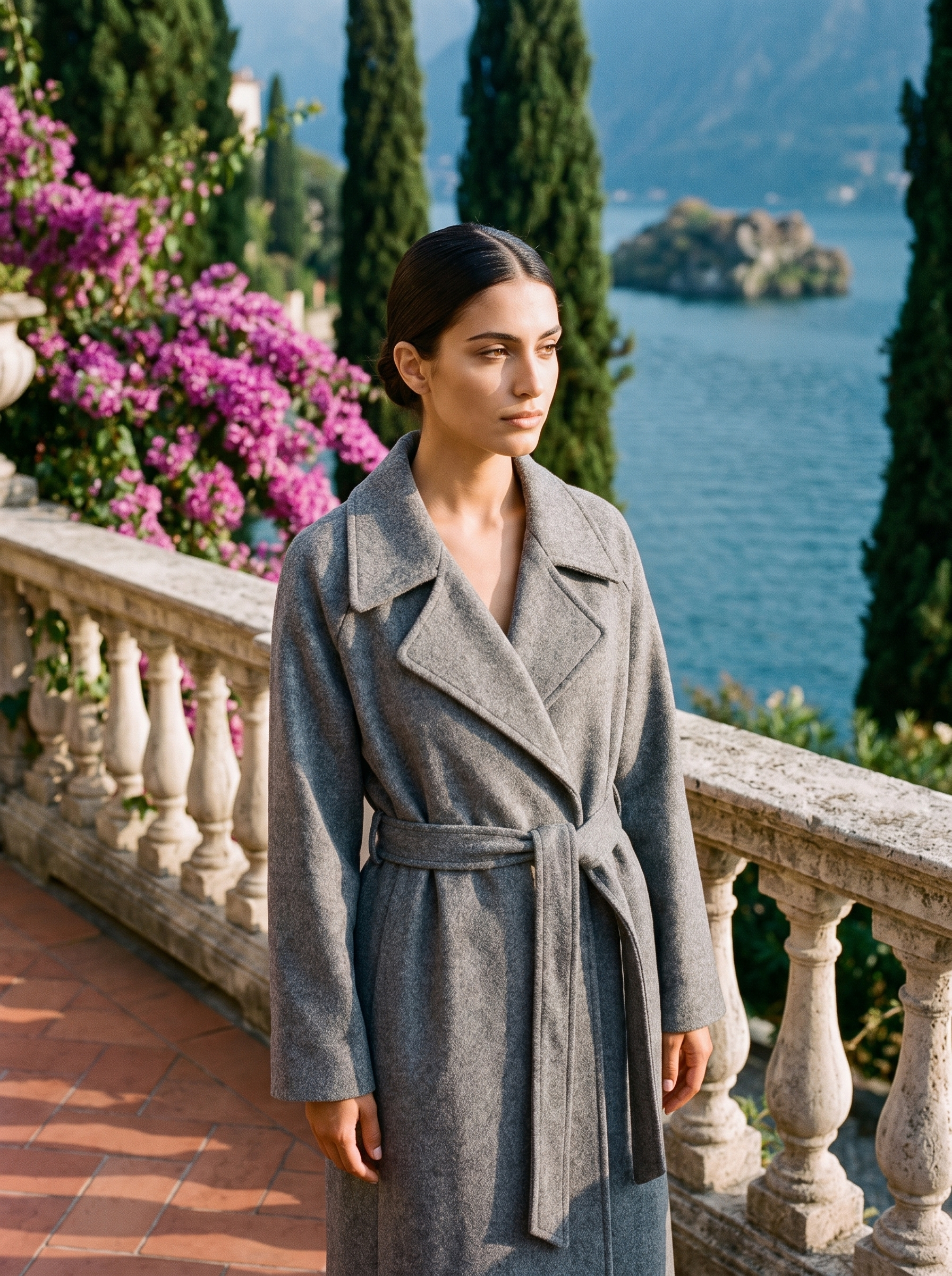 Woman wearing heather grey belted wool wrap coat on a Lake Como terrace