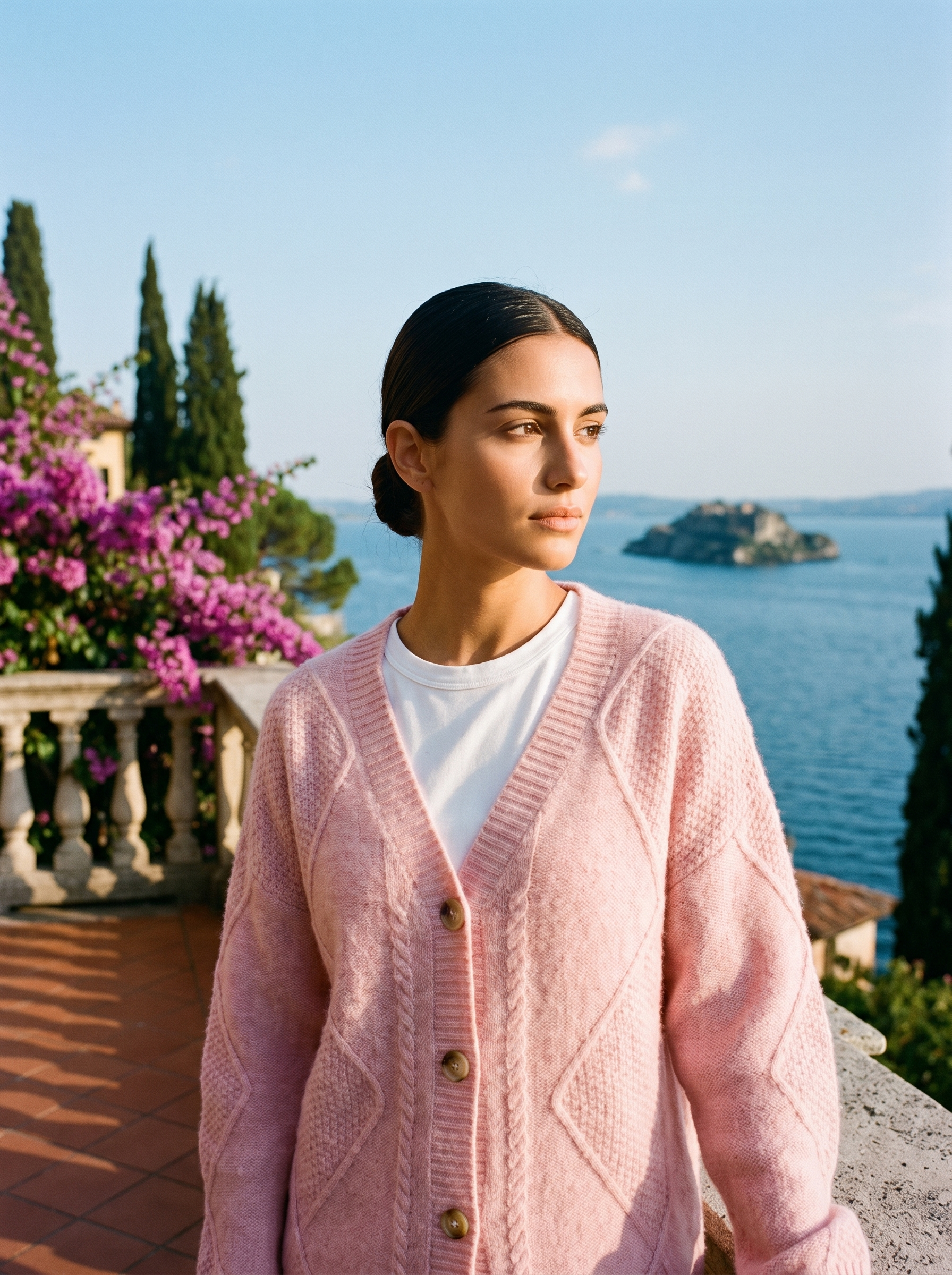 Woman wearing a pink cable-knit cardigan on a terrace overlooking Lake Como, old money style — Aveloire