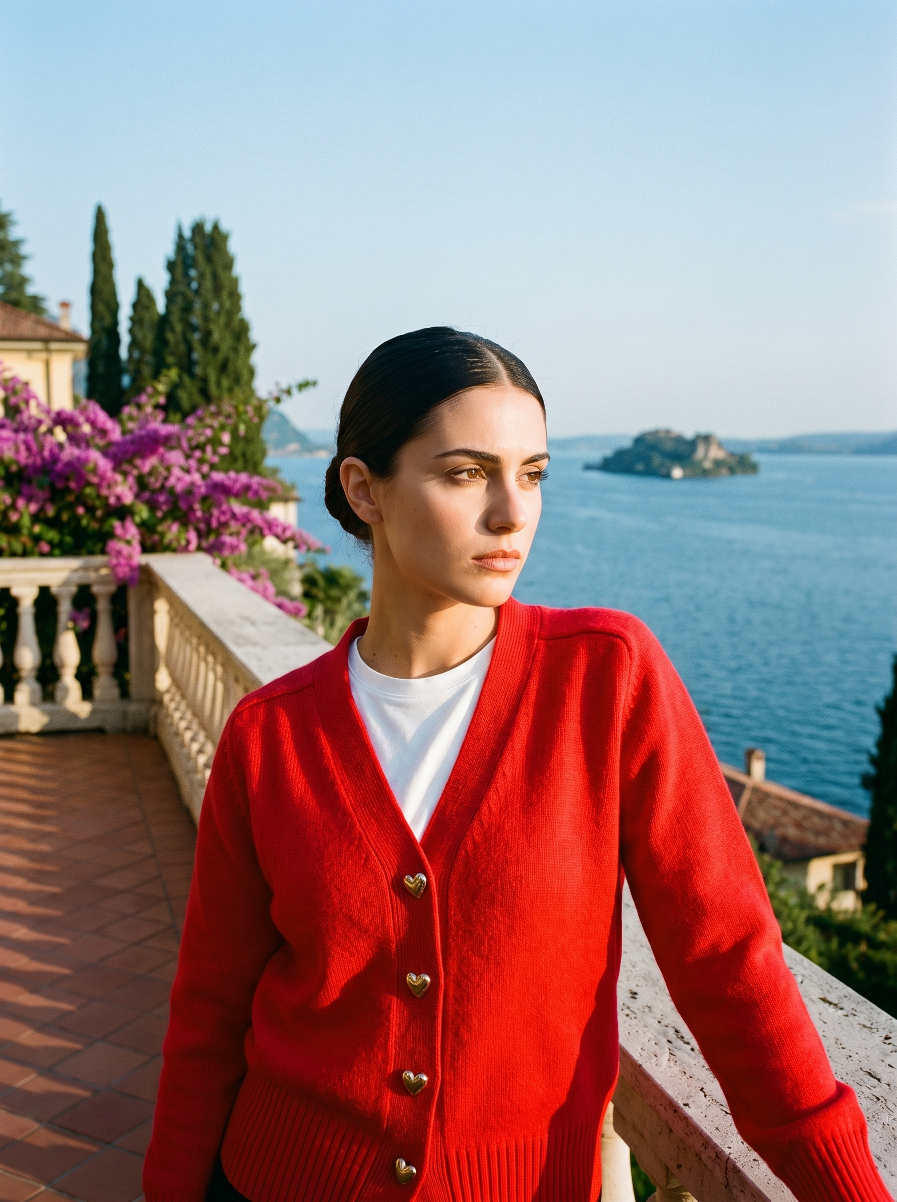 Woman wearing a red V-neck button cardigan on a terrace overlooking Lake Como, old money style — Aveloire